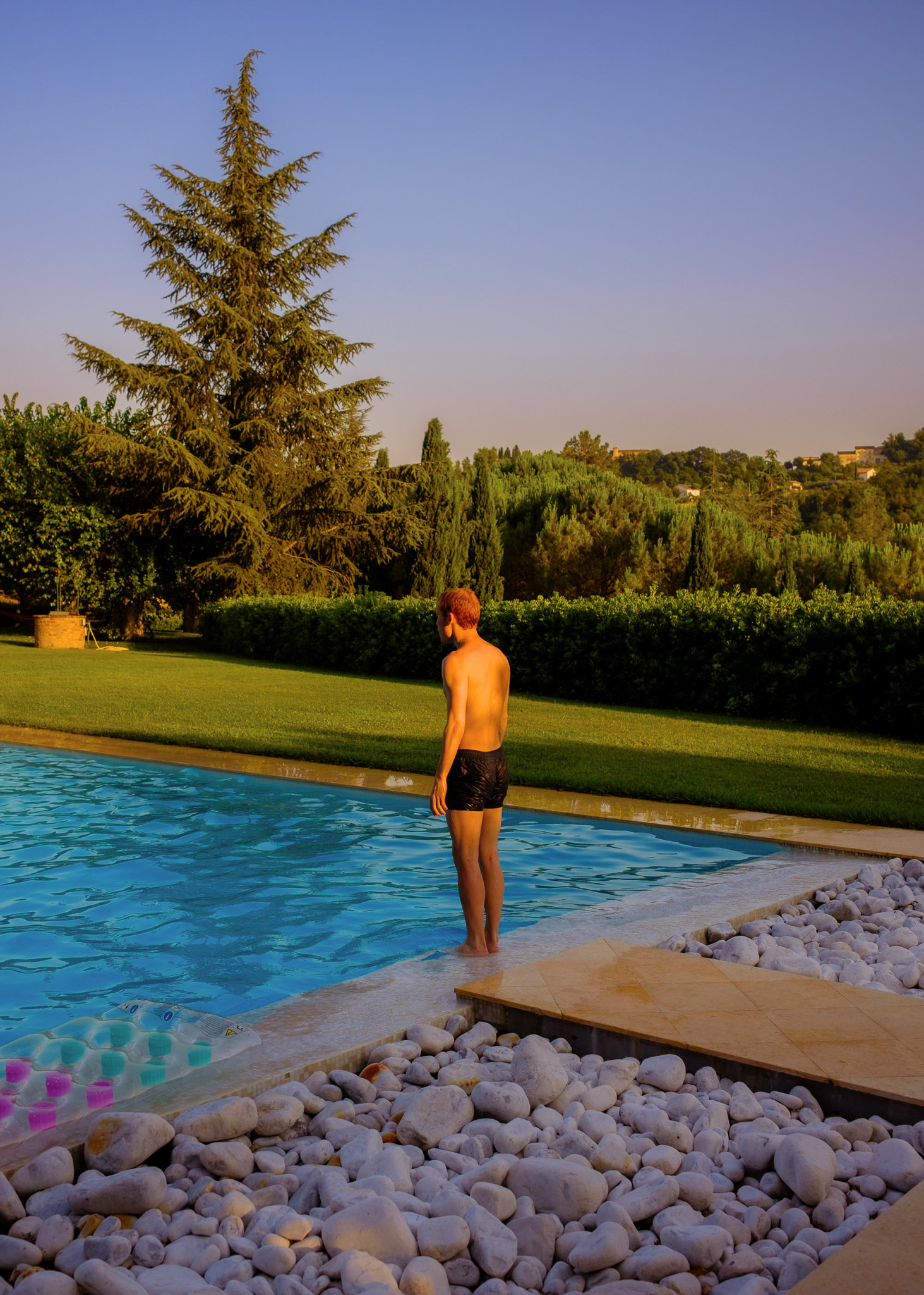 A person stands at the end of a swimming pool waiting to jump in. By Connor Redmond. 

