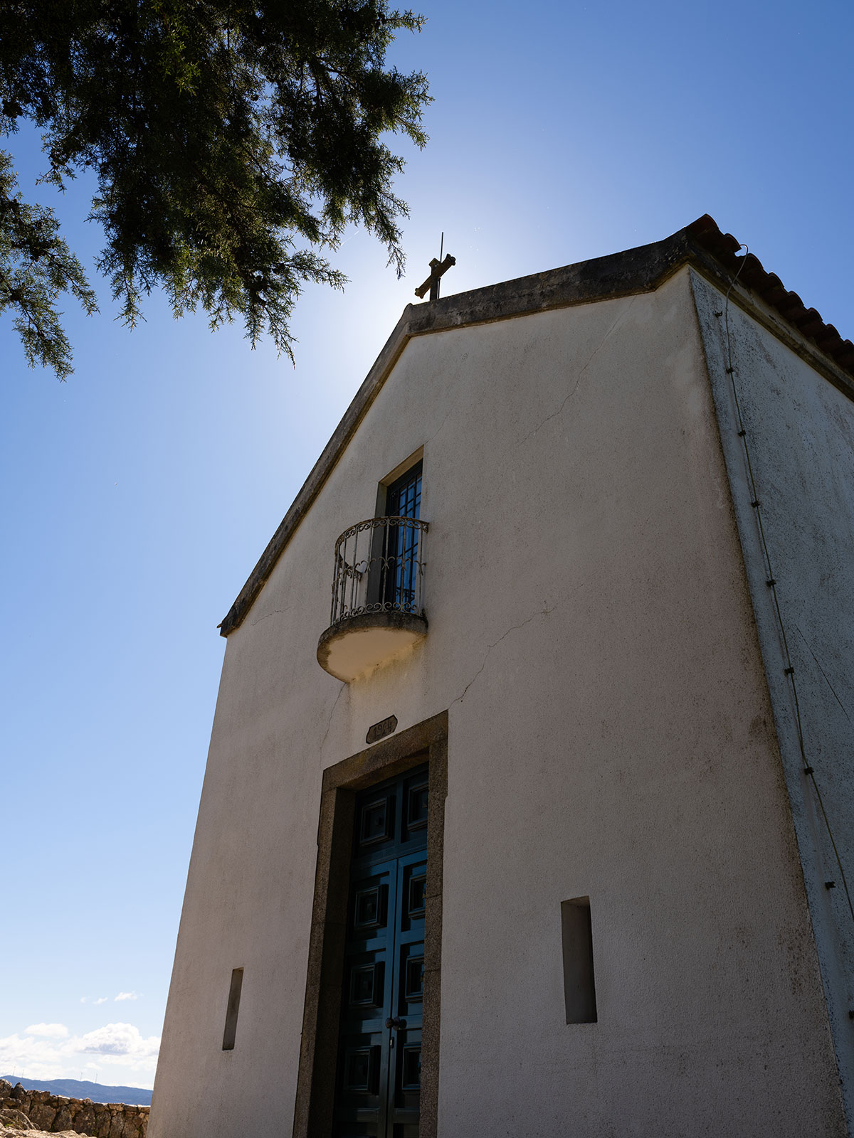 Looking up at a white church front with the sun behind it. Shot on the Fujifilm GFX100RF by Amy Moore.