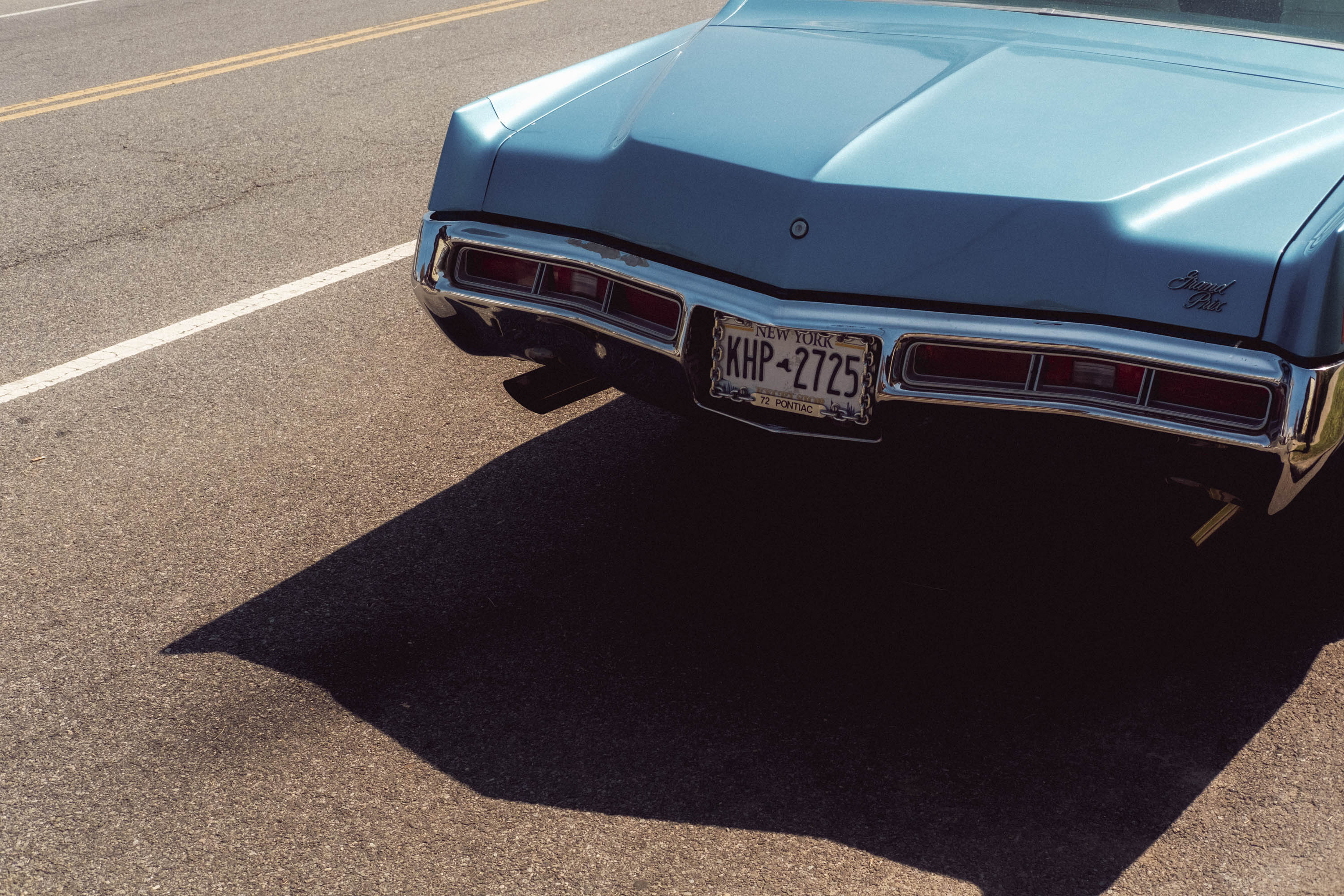 L'arrière d'une voiture vintage bleue garée sous le soleil direct. New York. Photo prise avec le X-Pro 3 par Ian Howorth.