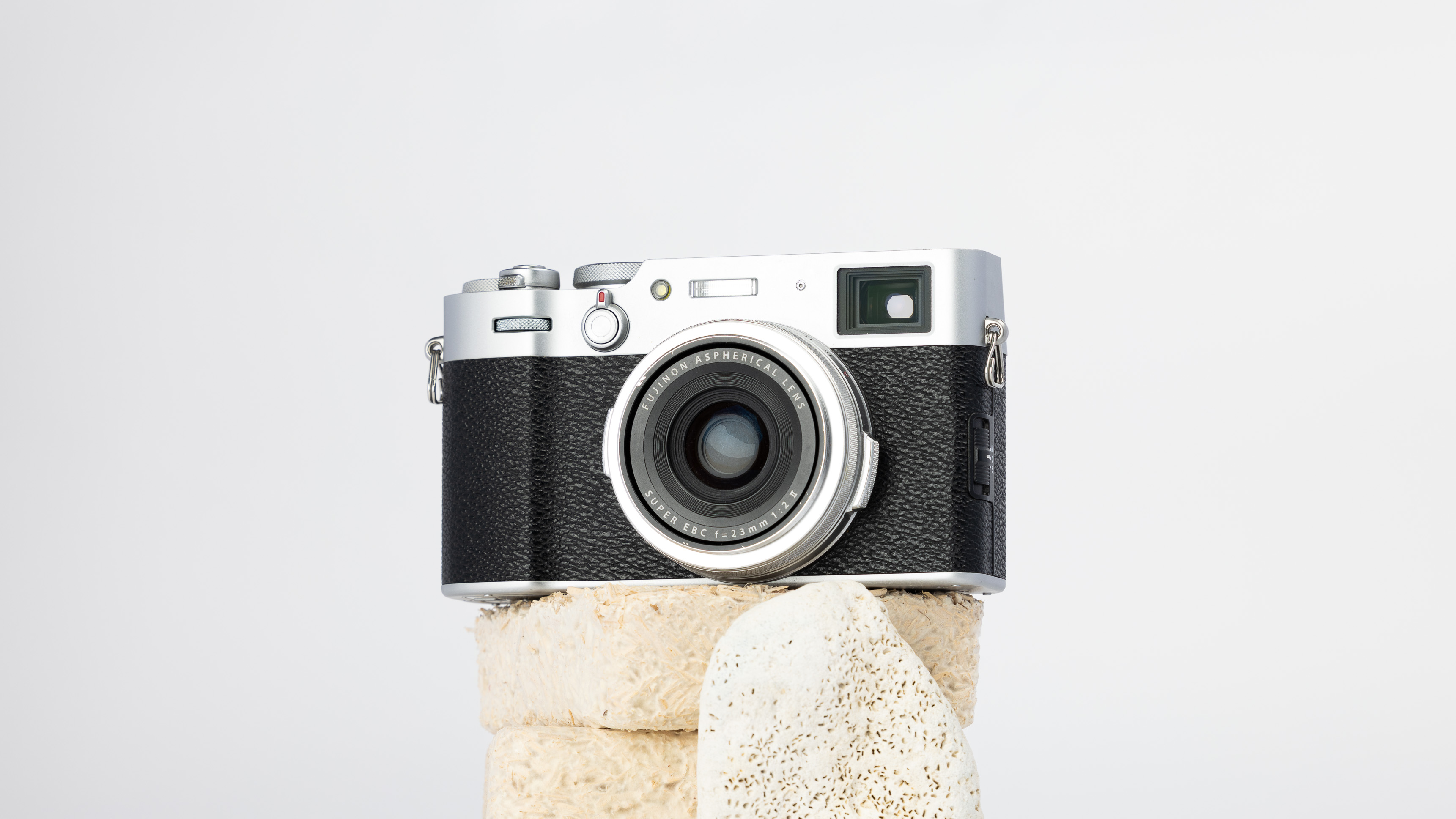 A product shot of a secondhand Fujifilm X100VI camera propped up on a rocky podium