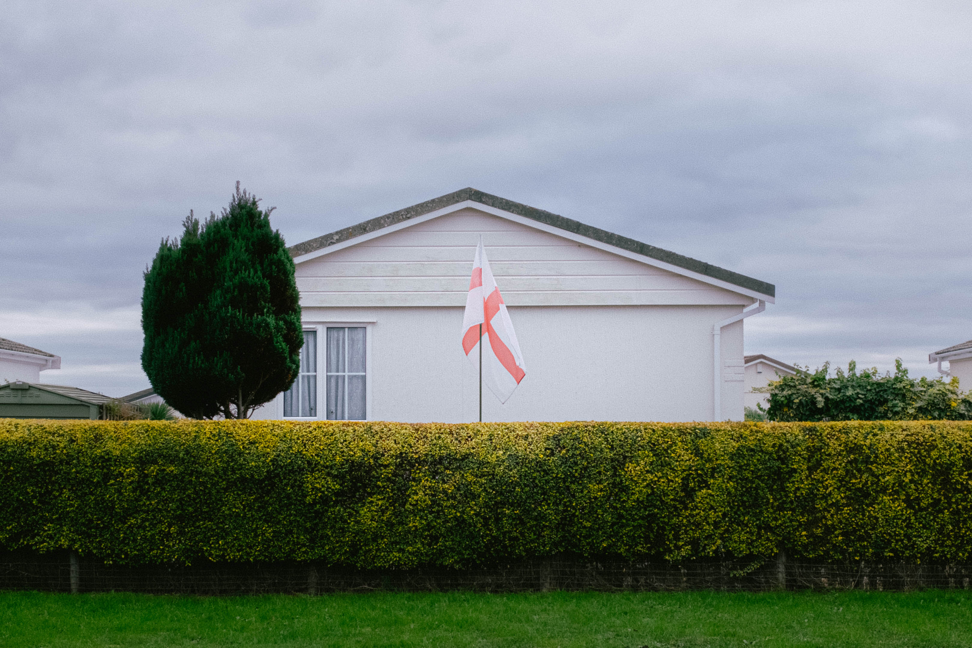 The flag of England sits on a flagpole outside a caravan park home. Taken on the Fujifilm X100VI by Connor Redmond.