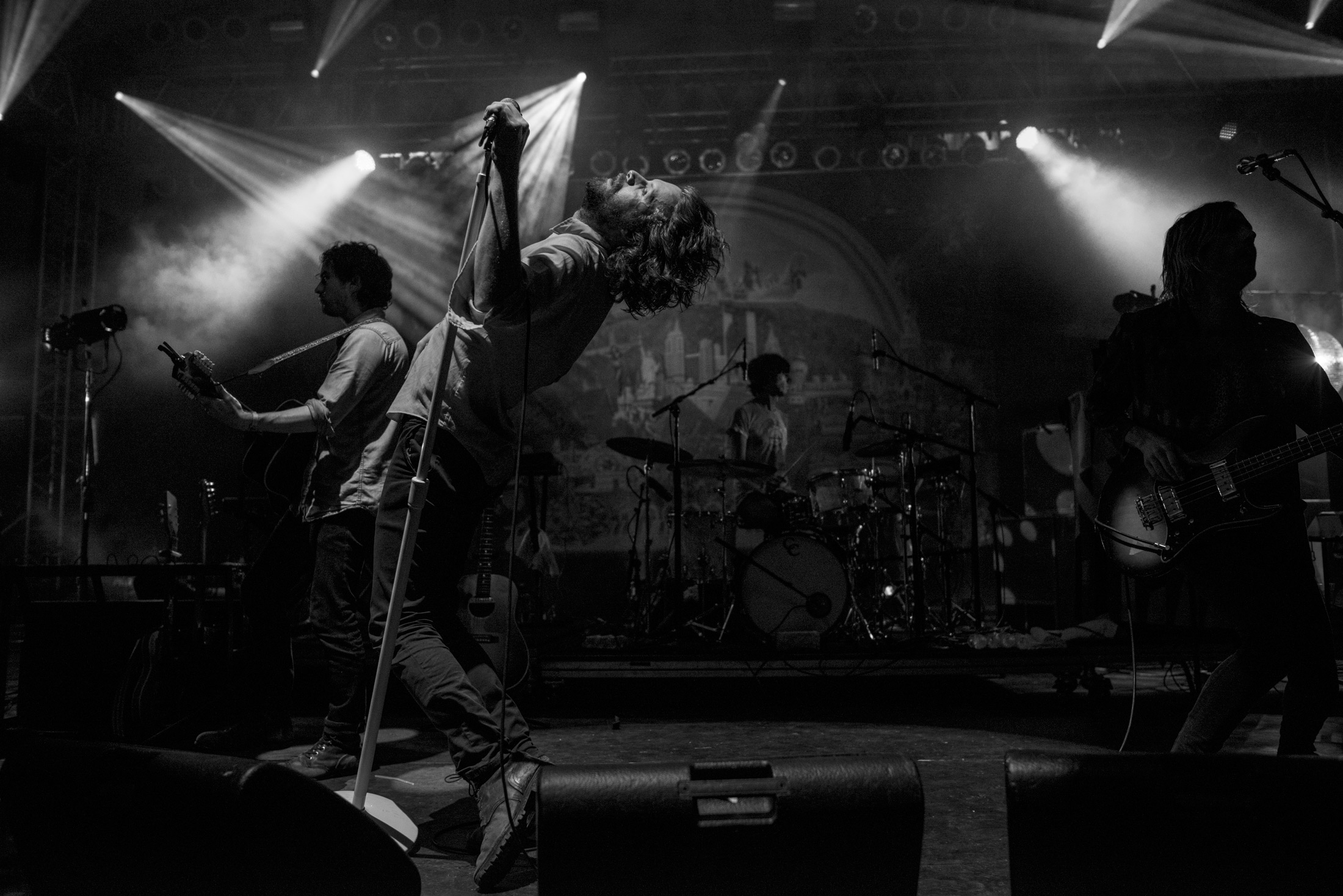 Father John Misty performing on stage bending backwards, photo by James Joiner.