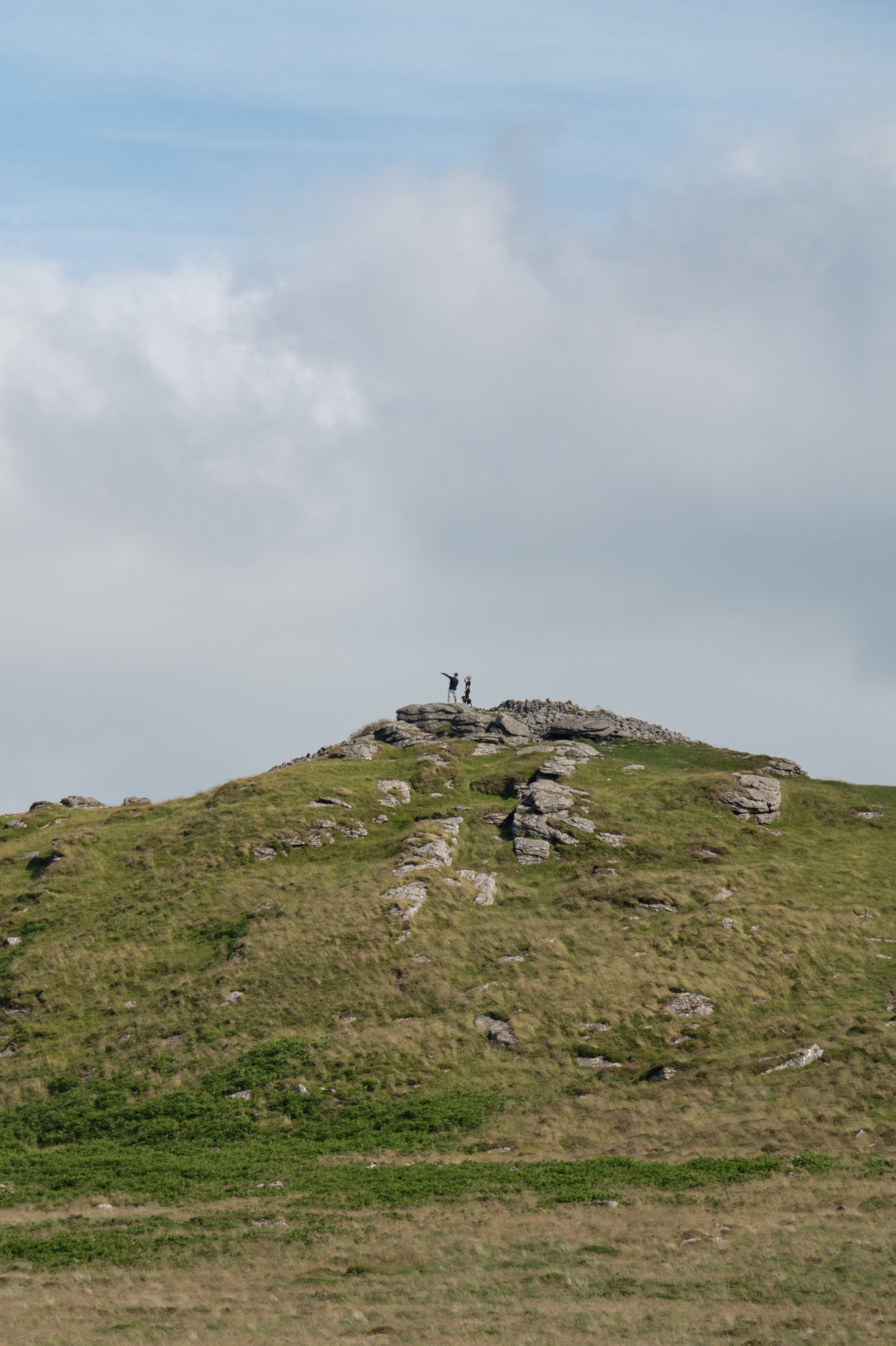 Two people and a dog look at the view from the top of rock formations on a hill. Photo by Amy Moore with the Panasonic S1R II.
