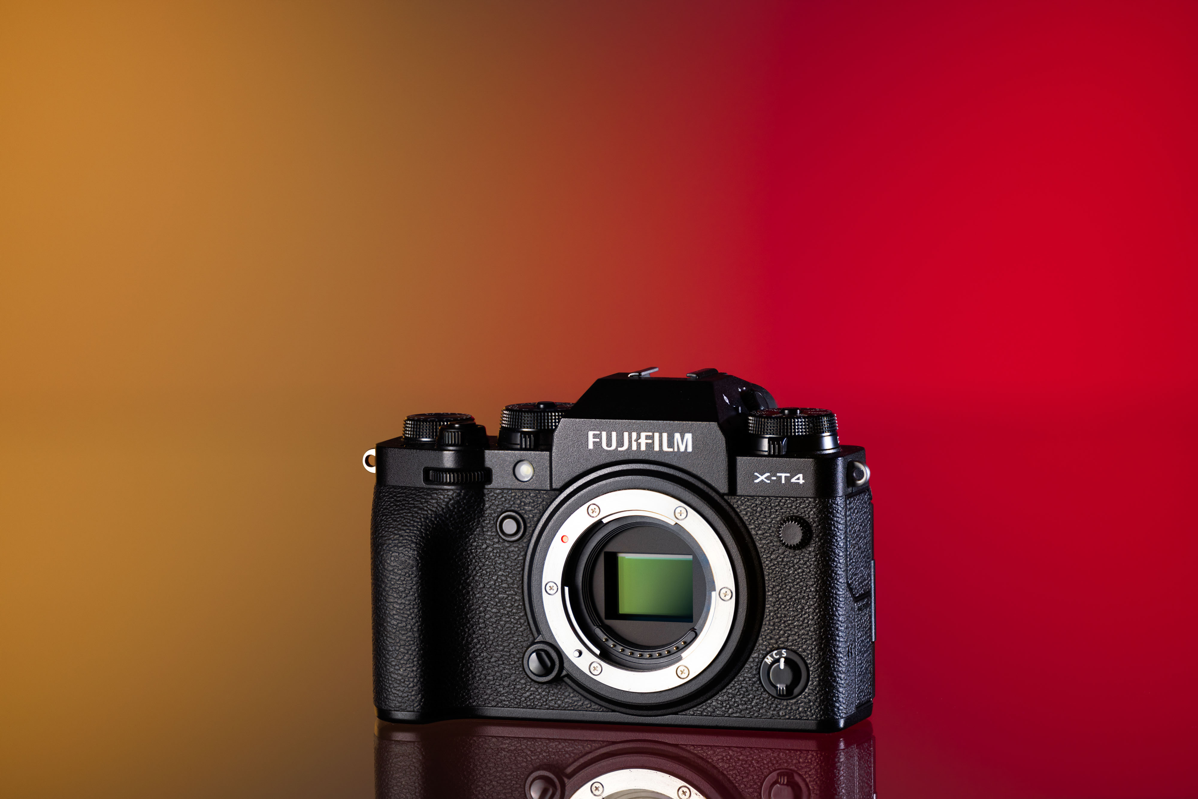 Cámara Fujifilm X-T4 de segunda mano sobre un fondo amarillo y rojo