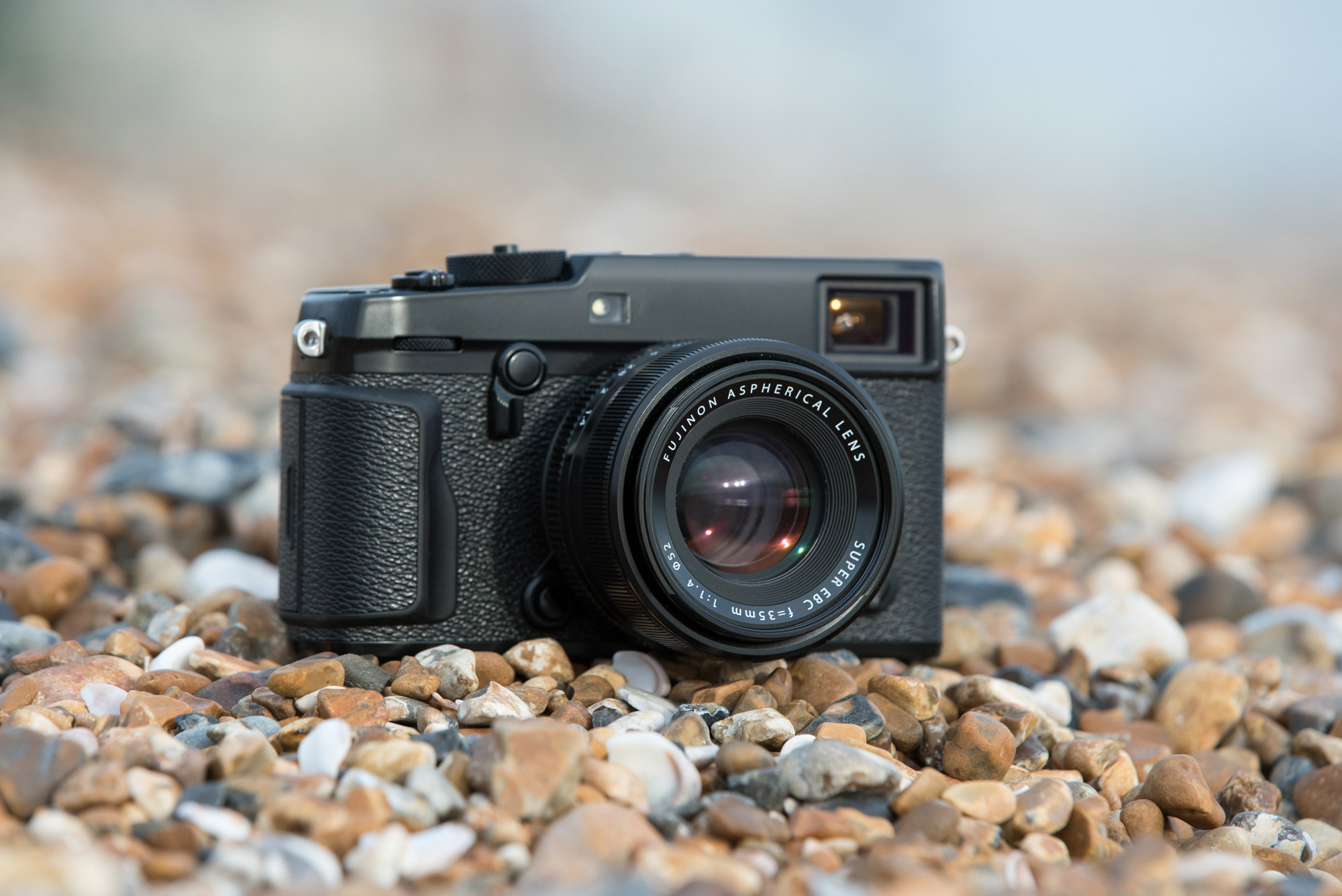 Appareil photo Fujifilm X-Pro 2 équipé d’un objectif Fujinon XF 35mm posé sur une plage de galets.