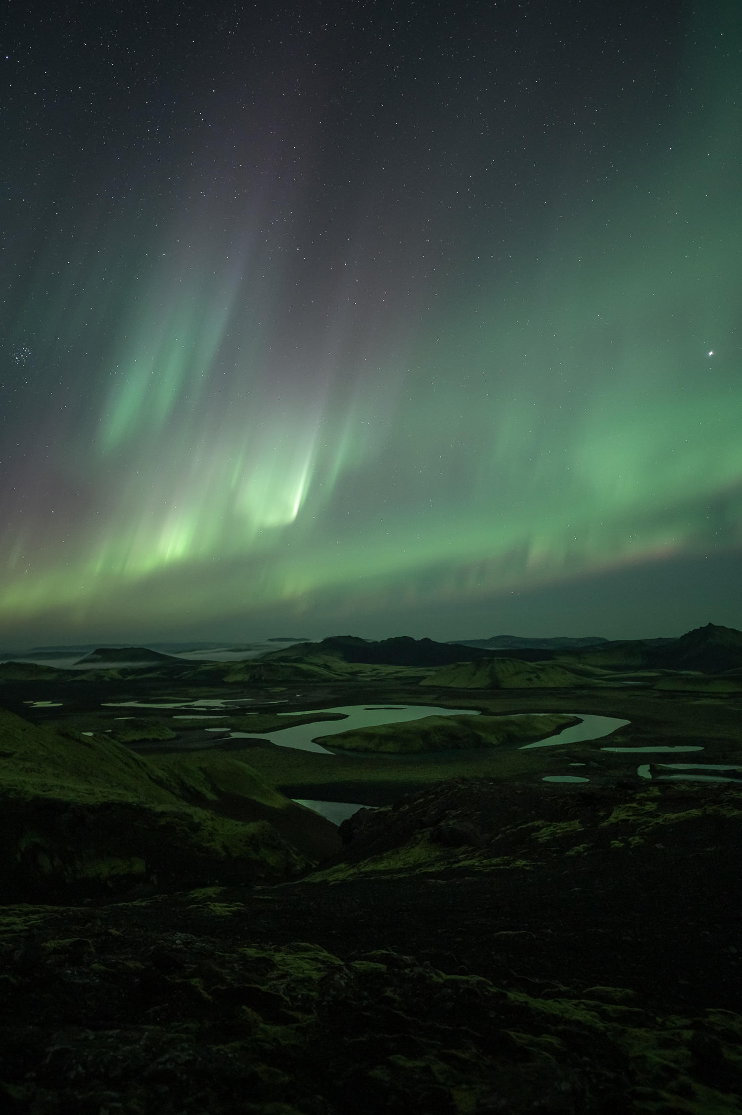 Hellgrüne Nordlichter beleuchten Flüsse, die durch eine Landschaft in Island fließen, aufgenommen von Paul Watson mit einer Nikon Z6