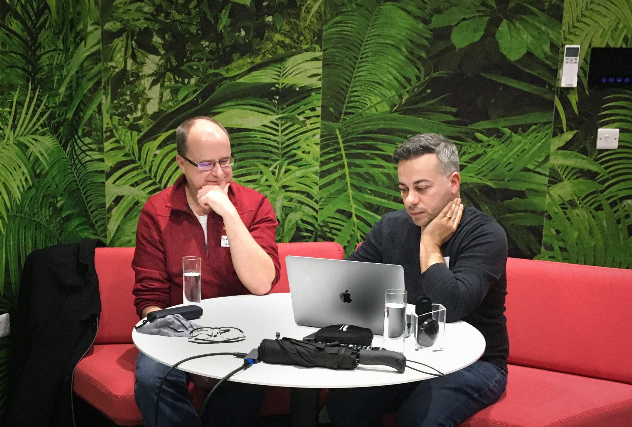 Two people sitting at a round desk looking at a laptop attending an MPB and codebar event in Brighton. 