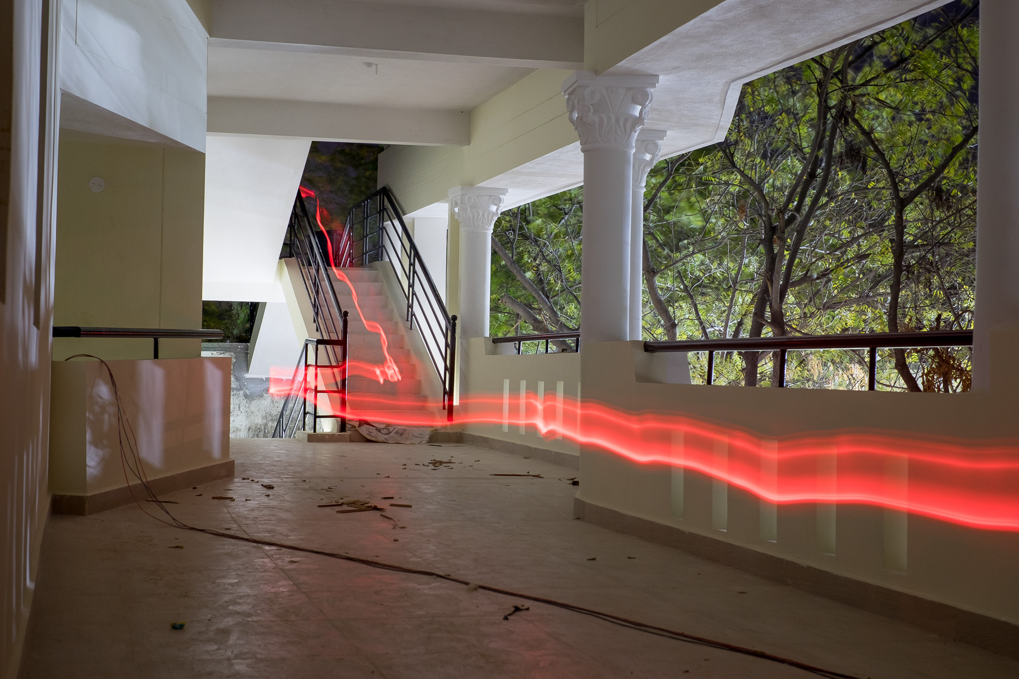 Een rood licht schilderij gaat van rechts van het frame naar links en een trap op. Door Michael Pacheco.