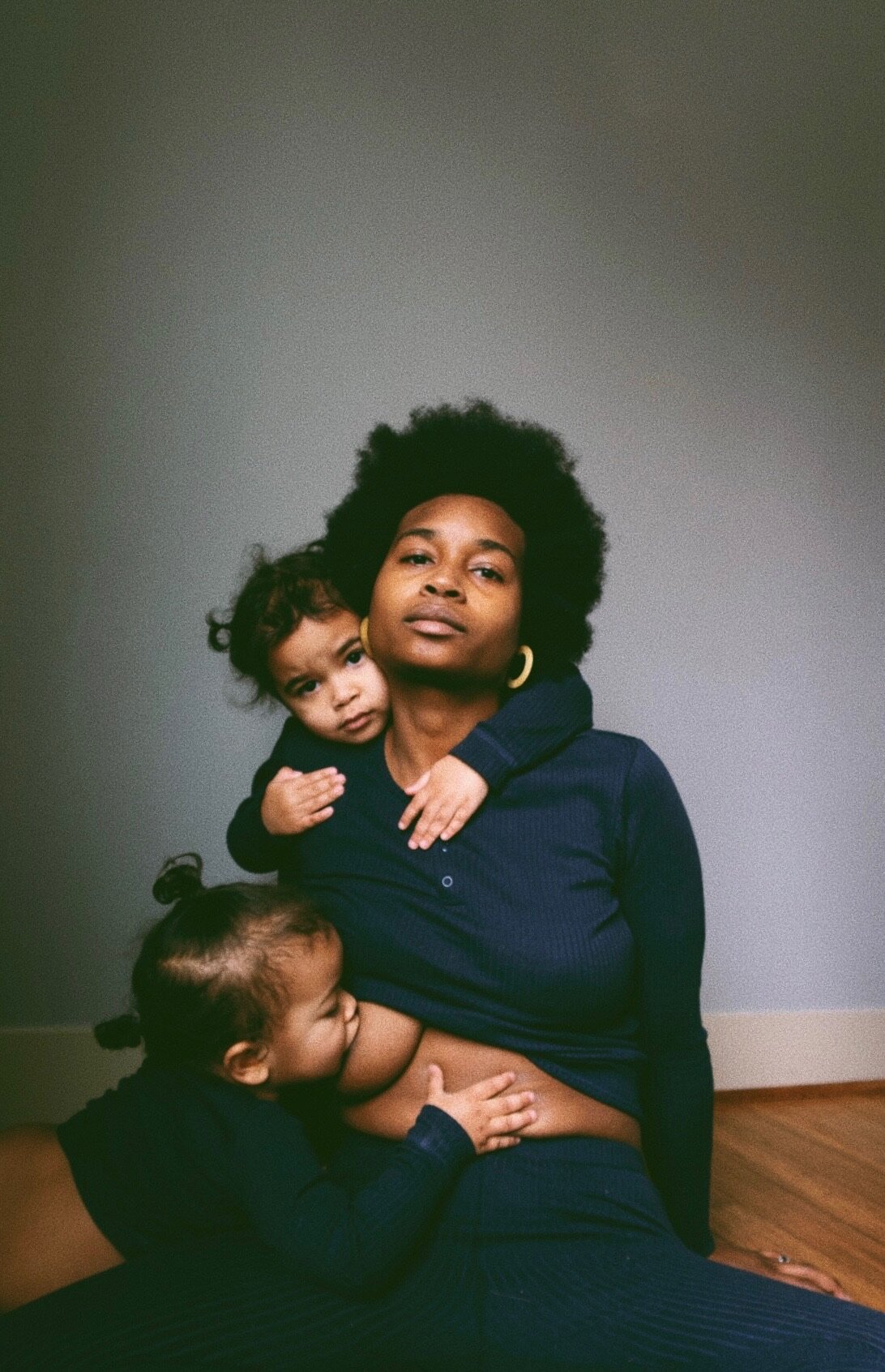 Portrait d'un parent assis sur un plancher en bois avec deux enfants, photographié par Bri McDaniel.