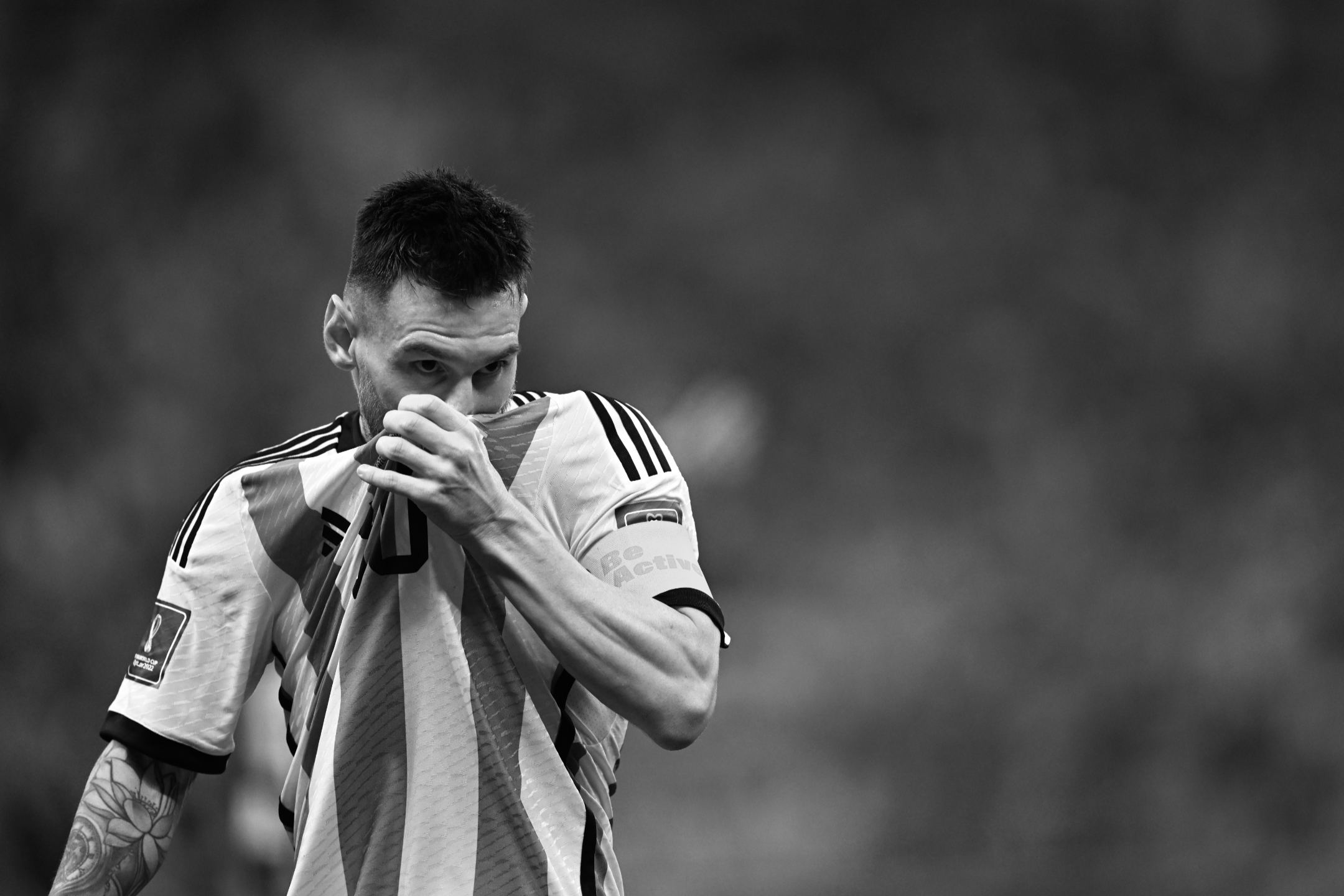 Ein Schwarz-Weiß-Foto des argentinischen Nationalspielers Lionel Messi, der sich während des Halbfinalsiegs seiner Mannschaft bei der Fußballweltmeisterschaft 2022 gegen Kroatien die Nase am Hemd abwischt, aufgenommen von Ryu Voelkel mit einer Nikon Z9.