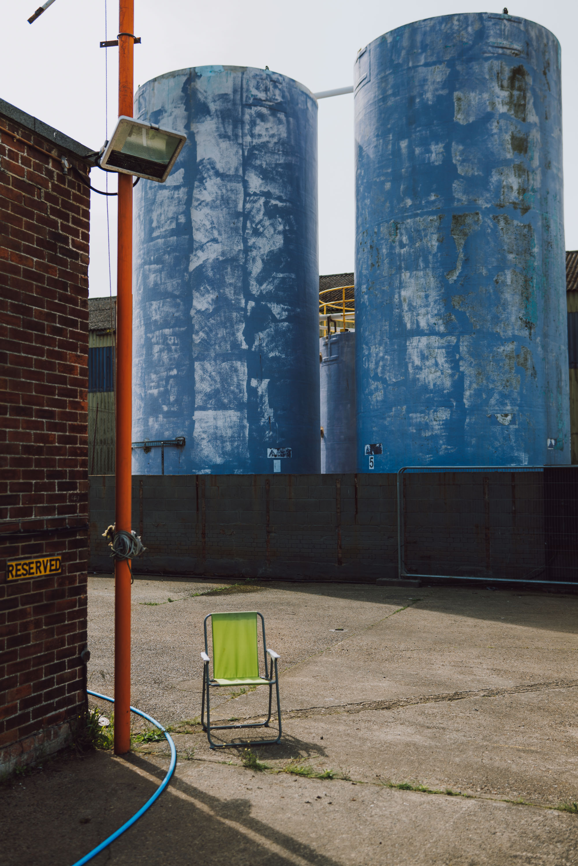 A green chair sits randomly in an industrial environment