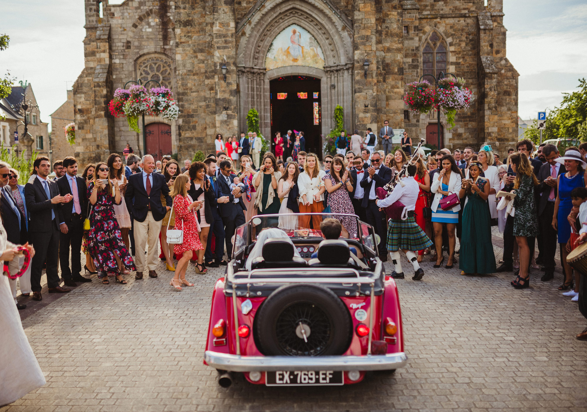 The couple's red car in front of the church. The guests are facing the front. Photo taken by Gauthier Le Guen with a Canon R6.
