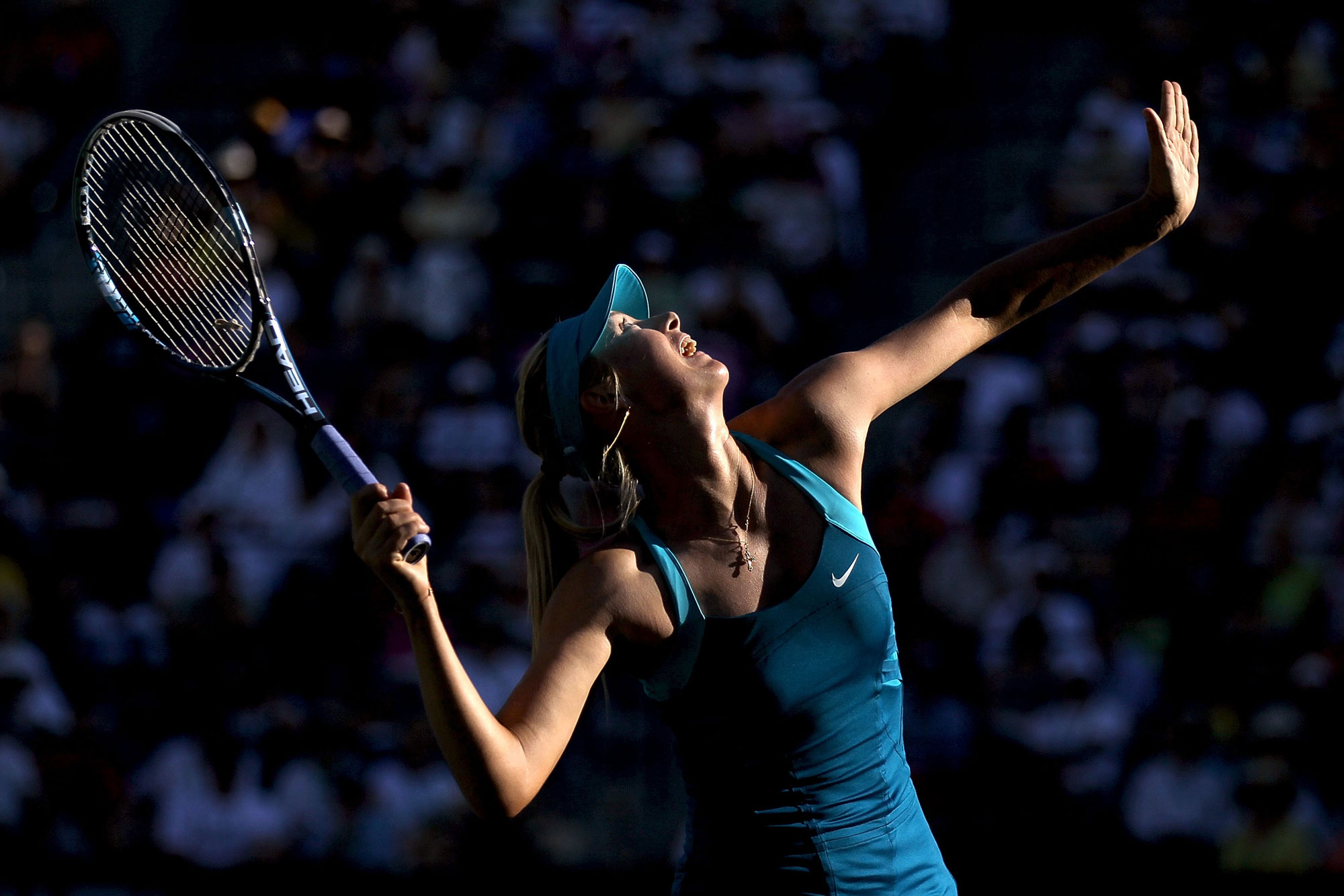 Maria Sharapova of Russia serves during the BNP Paribas Open at the Indian Wells Tennis Garden in Indian Wells, California. The light across her body is dappled, with her hand to the right of the frame and her racquet to the left. 