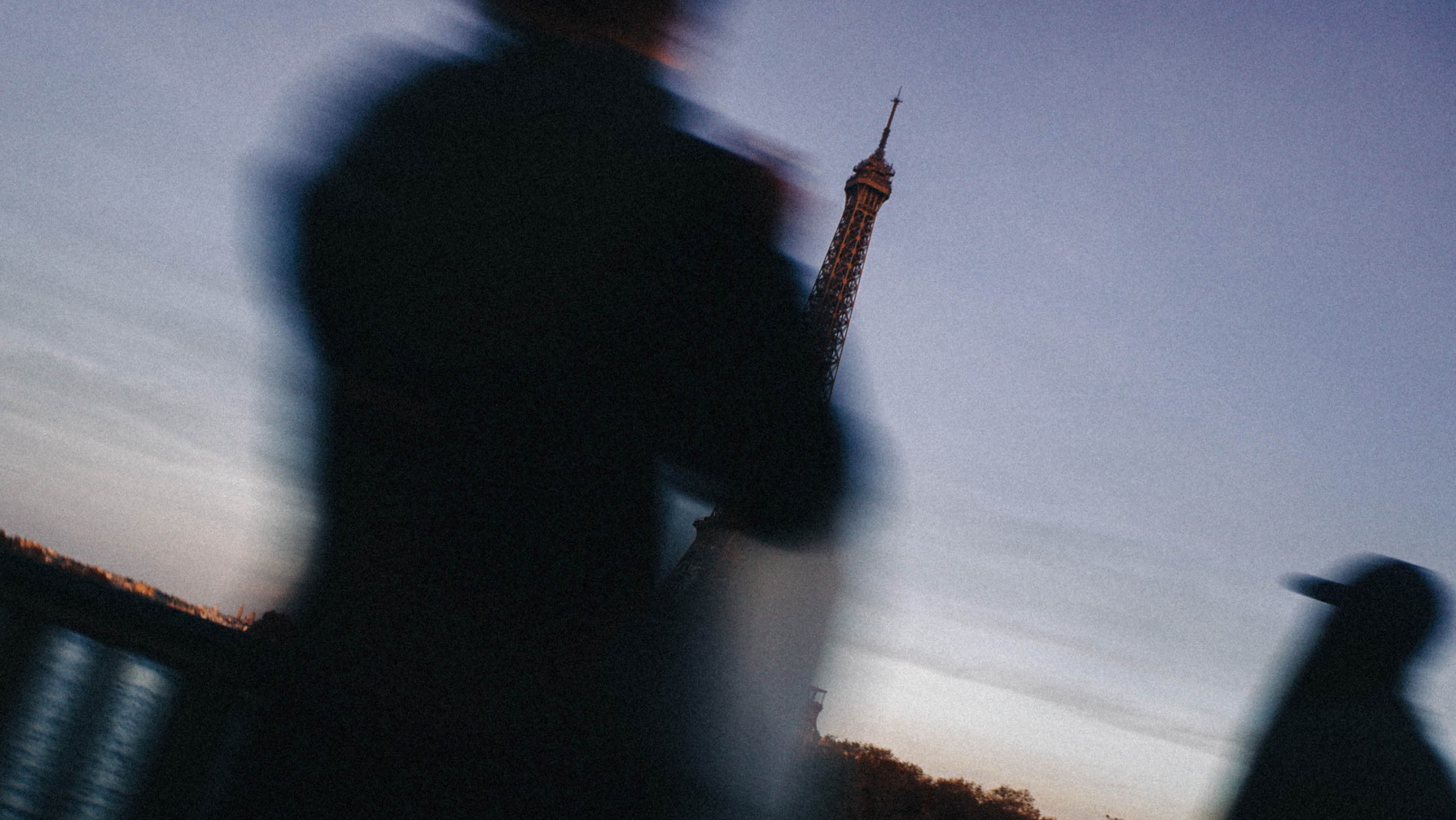 Artistic sunset shot of the Eiffel Tower framed by blurred passers-by on a Paris bridge. Shot by Wesley Verhoeve on a Fujifilm XF10.