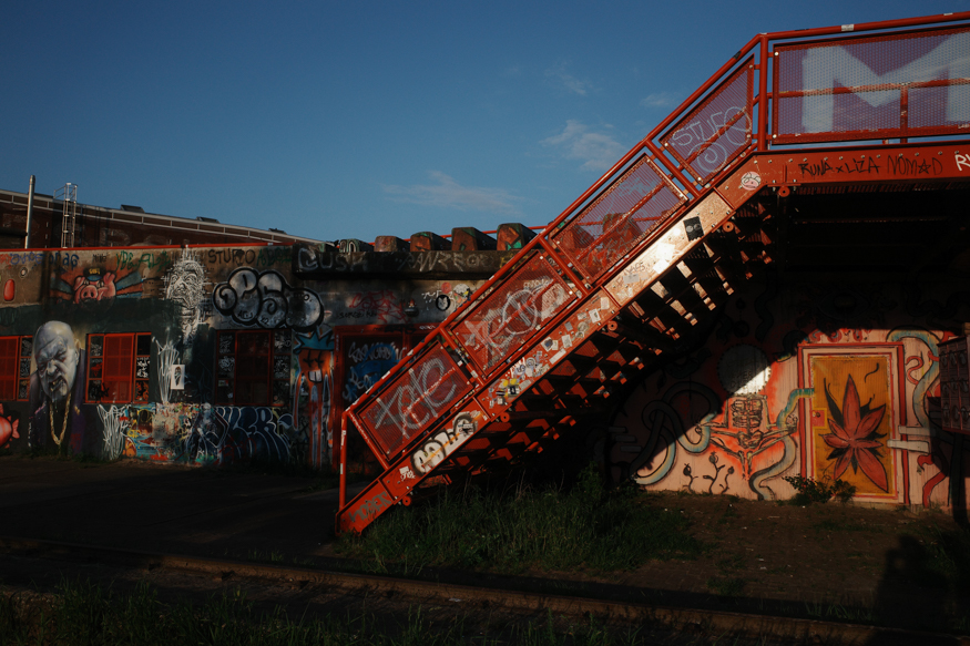 Een felgekleurde graffititrap op het NDSM-terrein in Amsterdam, vastgelegd in warm avondlicht vol textuur en kleur, gefotografeerd door Hermann Furin