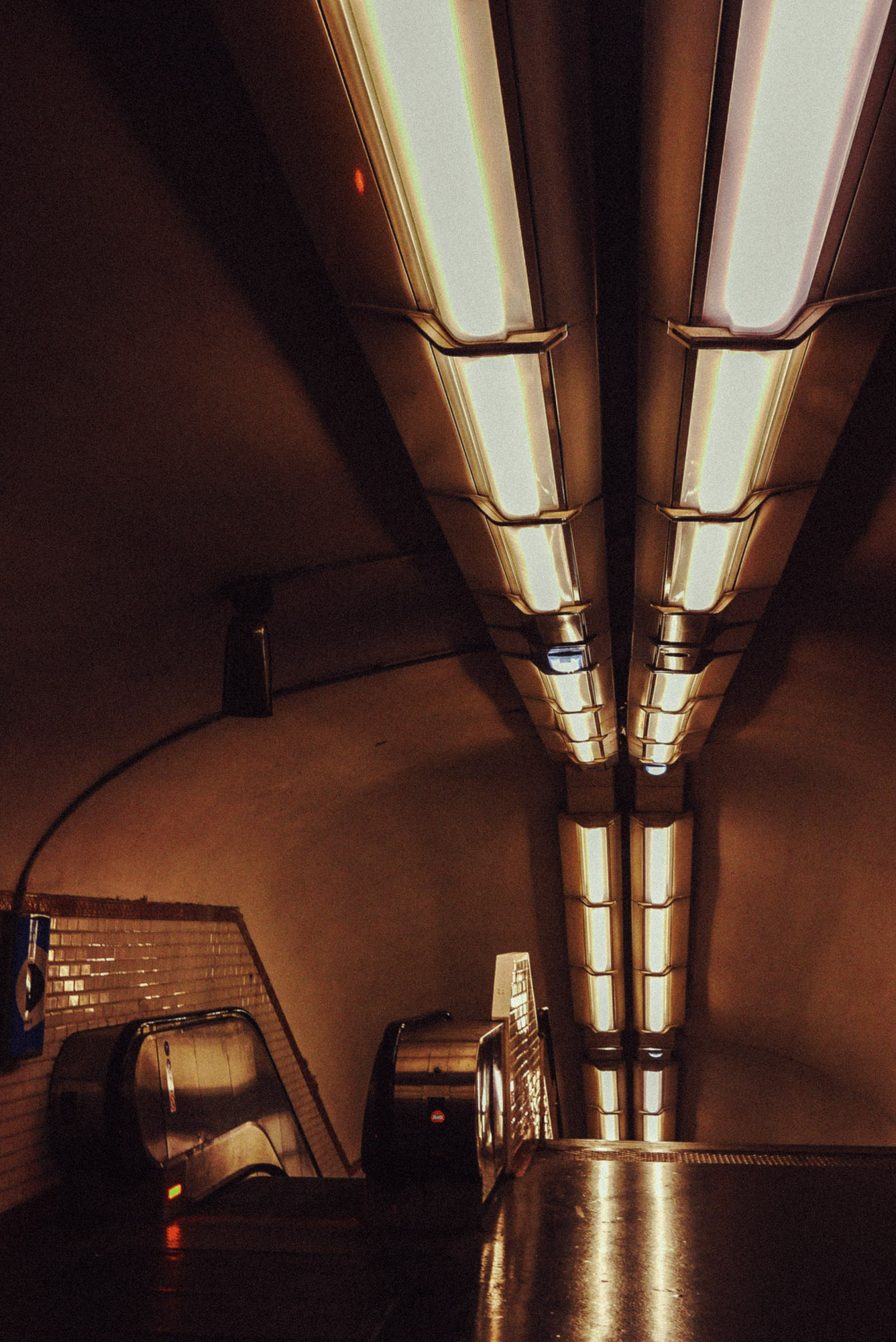 Streetaufnahme mit Rolltreppen in einer Pariser Métro-Station. Darüber lange fluoreszierende Deckenleuchten, die starke Linien und Reflexionen erzeugen. Aufgenommen von Wesley Verhoeve mit einer Panasonic Lumix GF1.