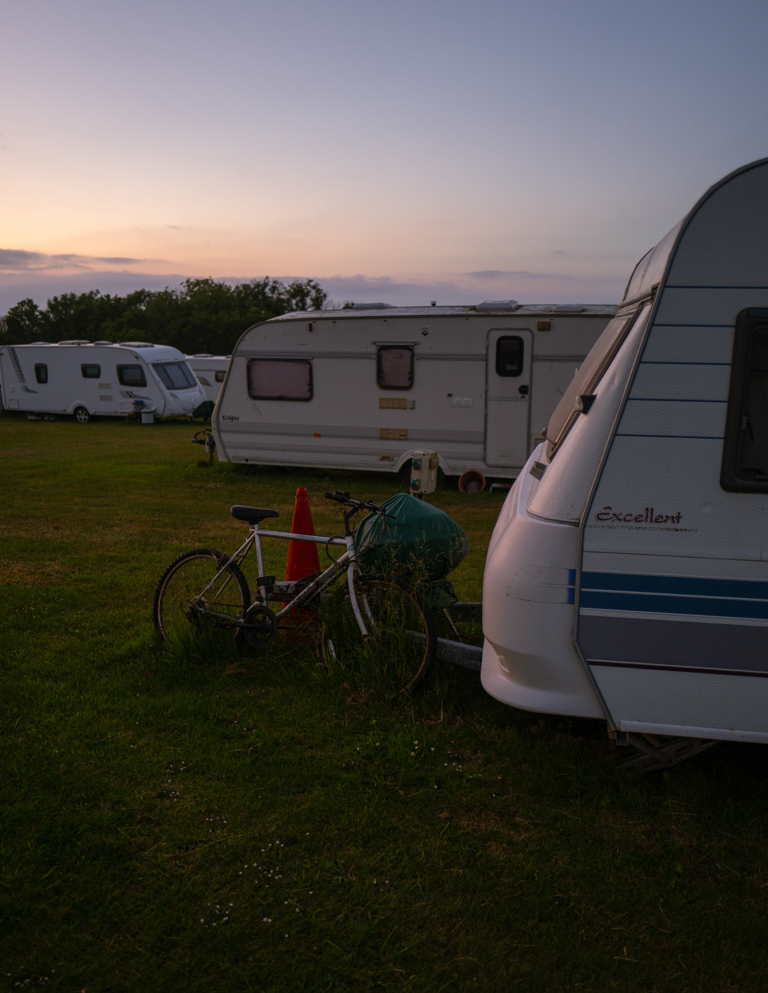 A bicycle leaning against a caravan in a holiday resort in Cornwall at sunset. By Connor Redmond. 