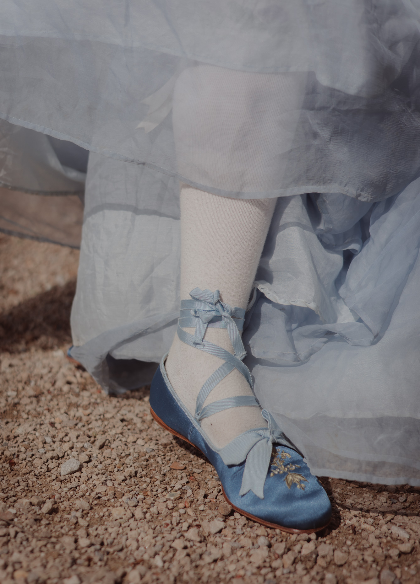 A model wearing white tights and light-blue shoes on a gravel path, photo by Liza Roberts with a Canon EOS R6