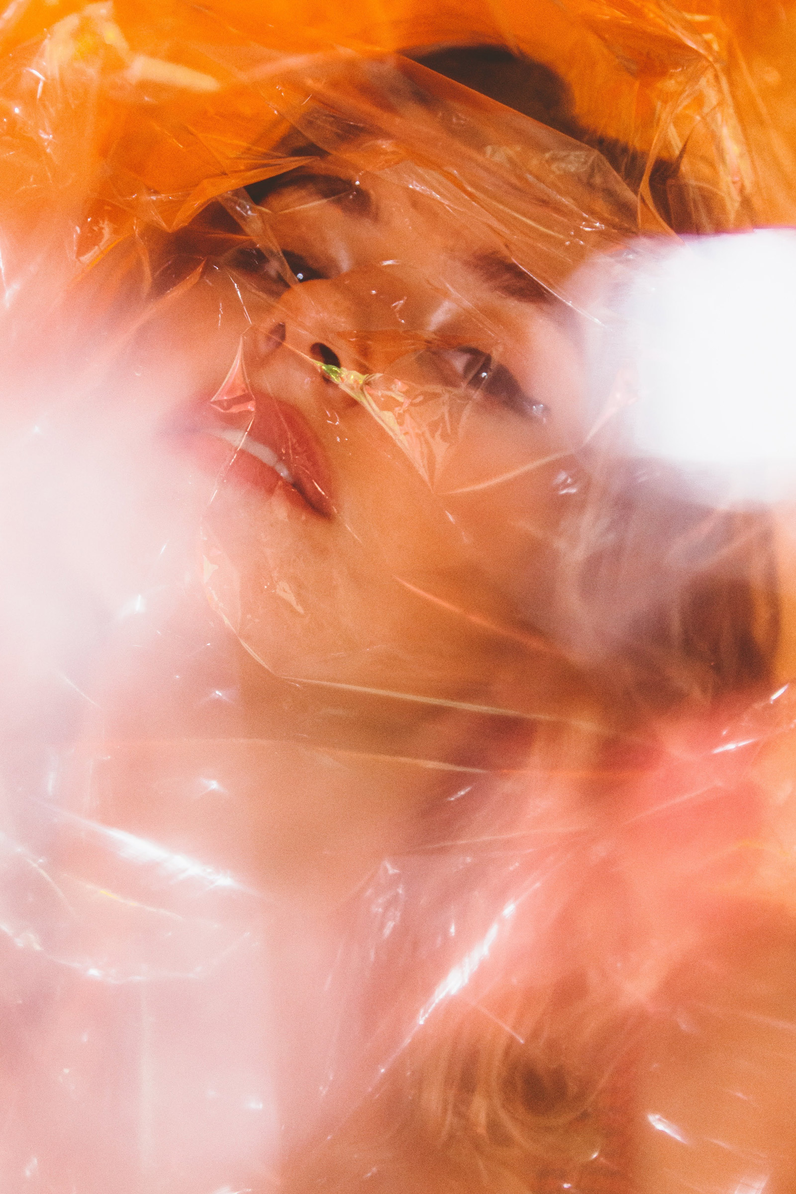 A model covered in a plastic sheet looking towards the camera, shot by Mariam Salahvarzi with a Sony A7S III