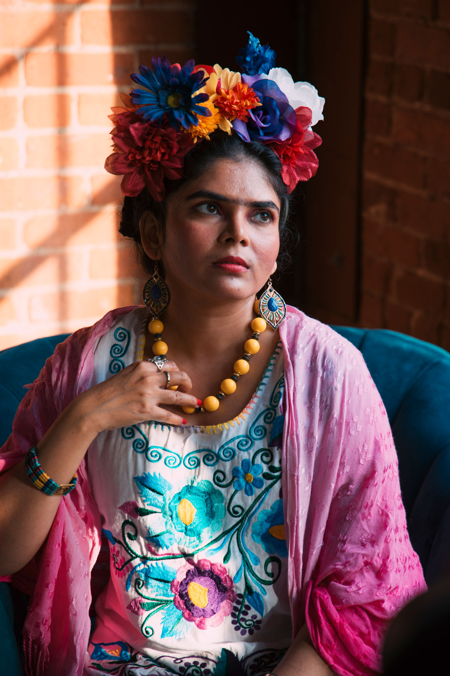 Frida Kahlo cosplayer sits in a chair.