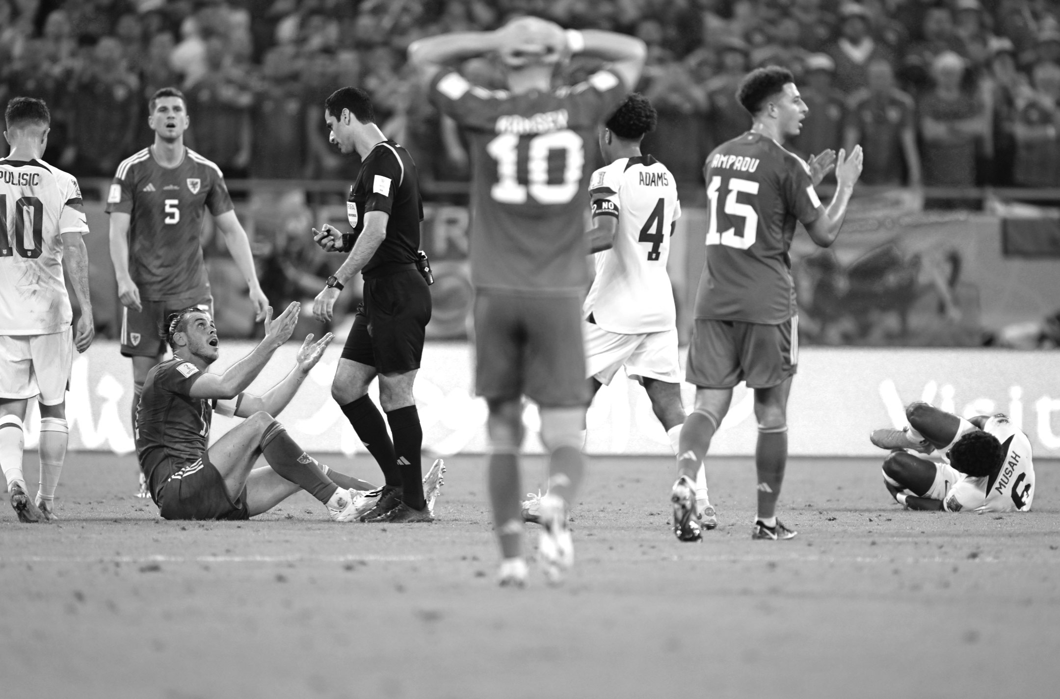 Ein Schwarz-Weiß-Foto des Schiedsrichters Abdulrahman Al Jassim, der mit dem walisischen Kapitän Gareth Bale spricht, nachdem er den Mittelfeldspieler der USA, Yunus Musah, während des Unentschiedens bei der Fußball-Weltmeisterschaft 2022 angegriffen hat. Aufgenommen mit einer Nikon Z9 von Ryu Voelkel