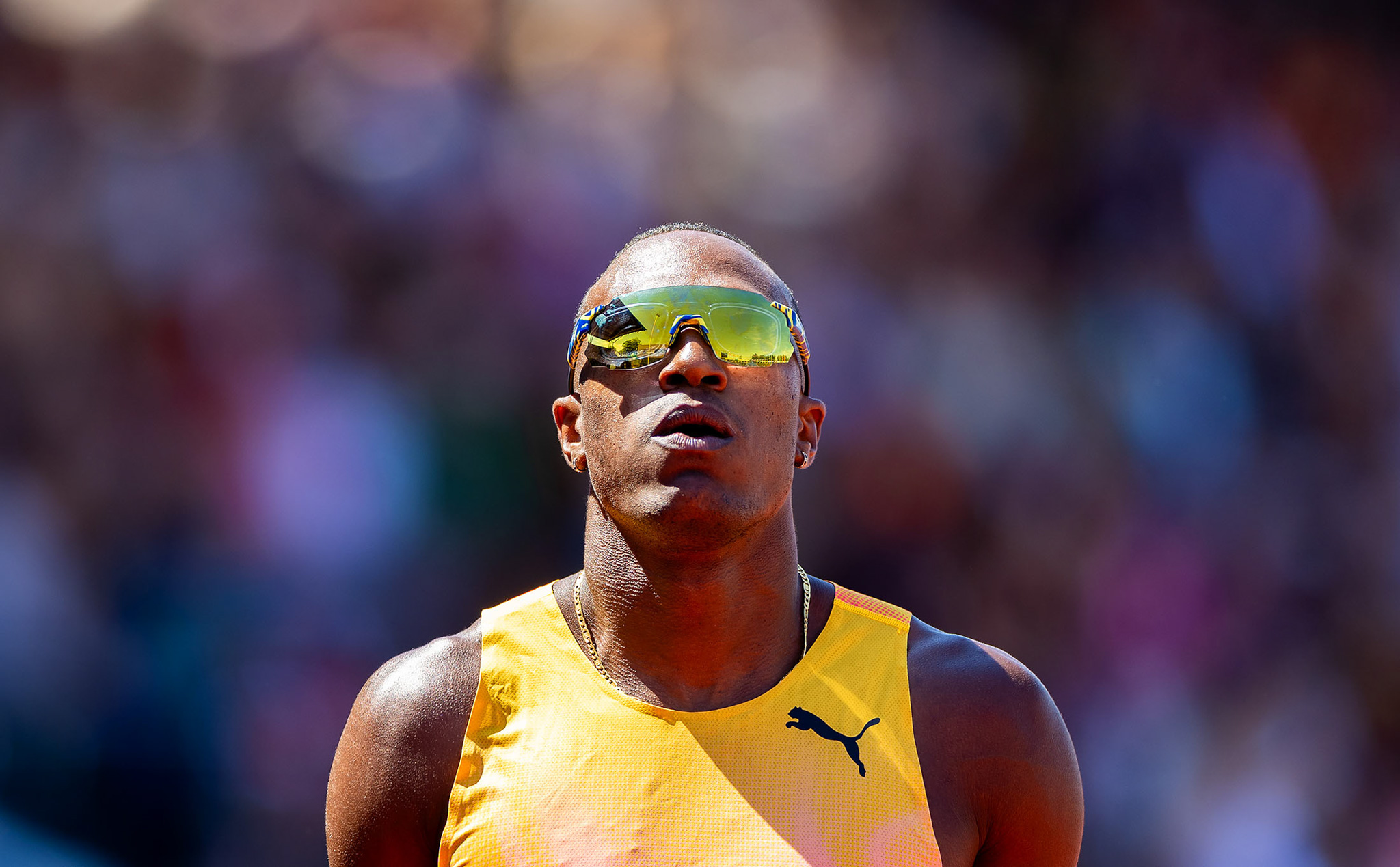 An athlete with yellow/green sunglasses on looking directly towards the camera. By Iris van den Broek.