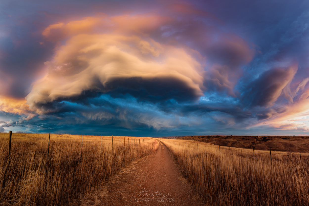 Clouds roll over a field at dusk.