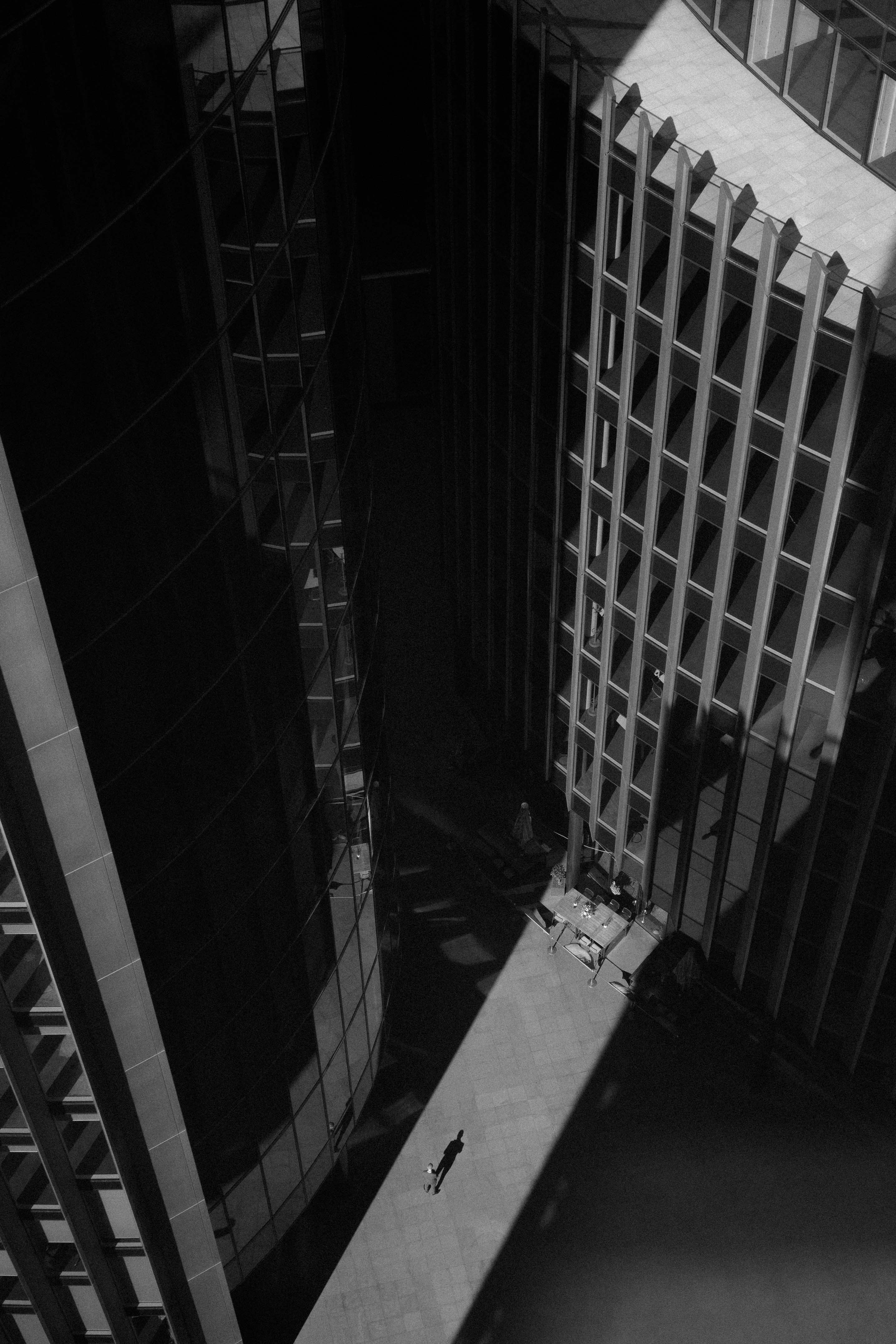 Black and white image of a person standing in a beam of light amongst skyscrapers

