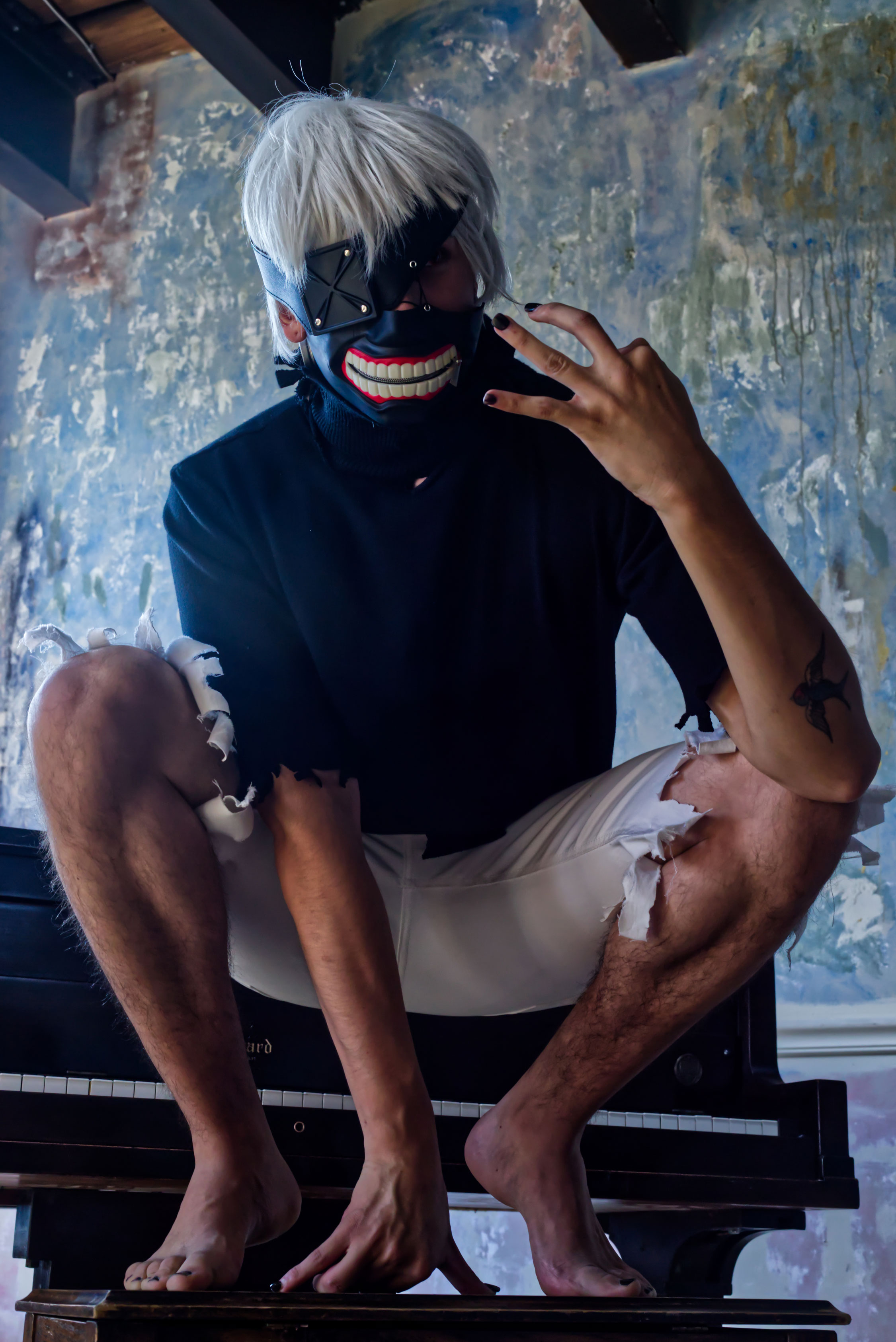 Anime cosplayer poses on a piano bench.