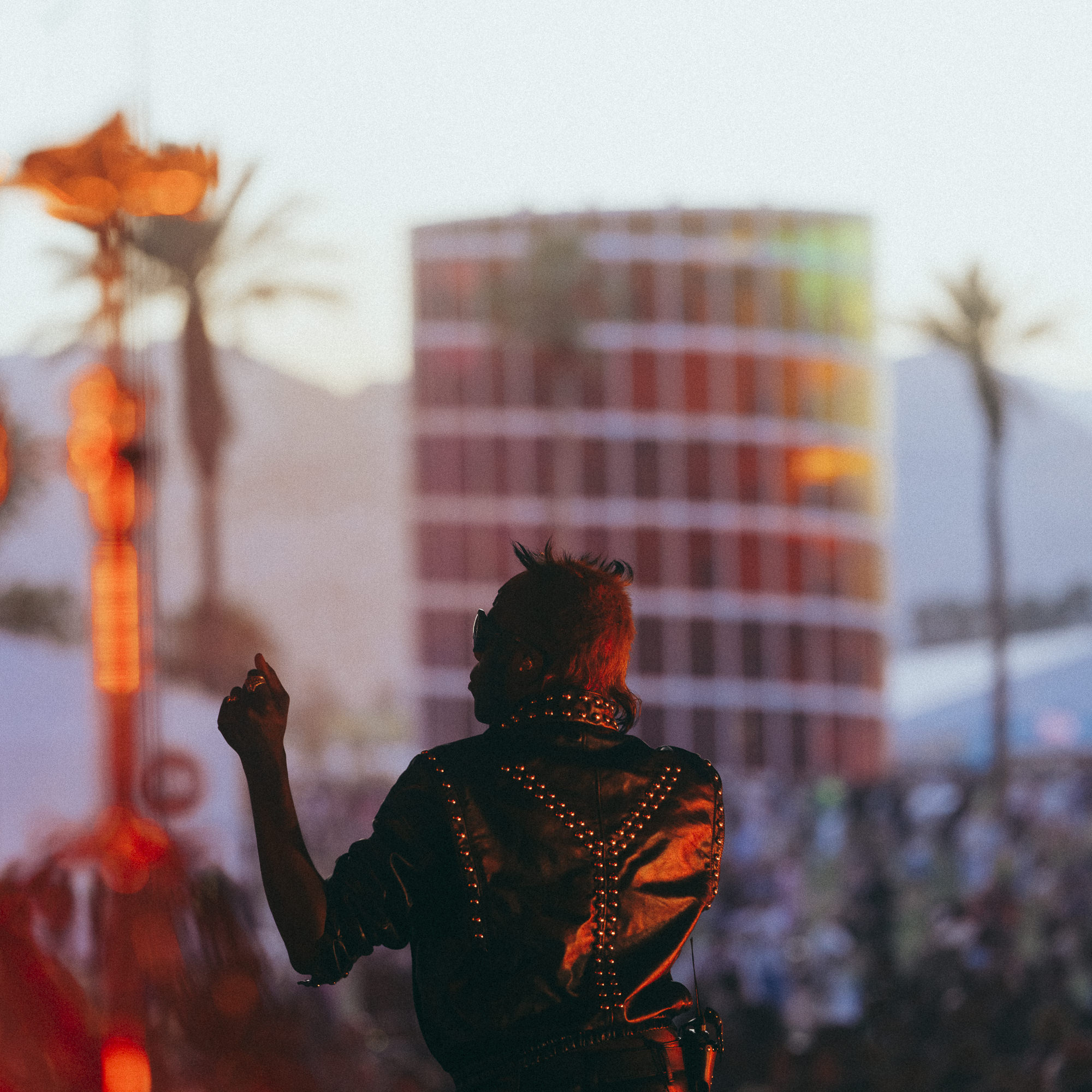 Yves Tumor on Gobi stage at 2023 Coachella Valley Music and Arts Festival at sunset with rainbow sculpture in the background.