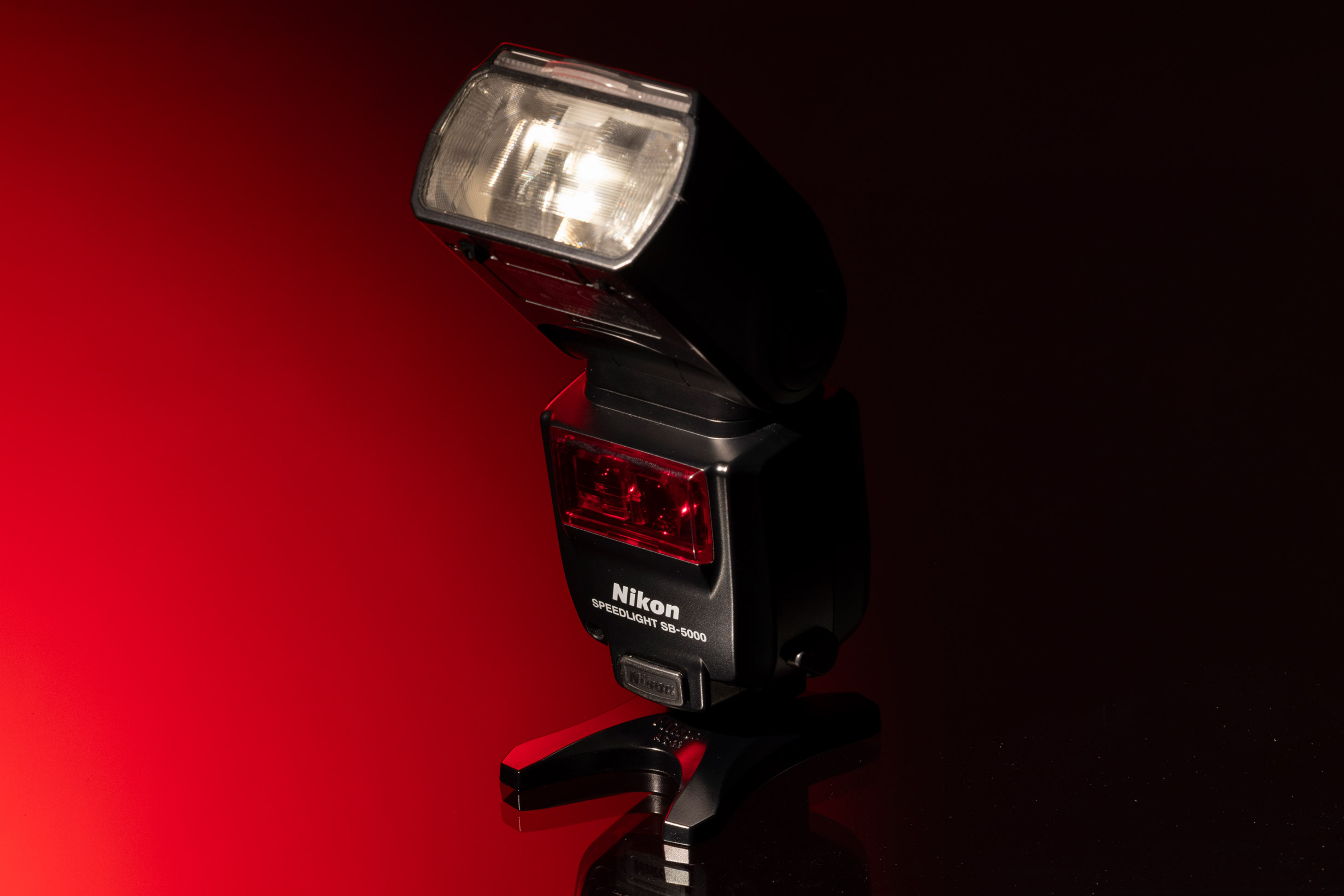 Nikon SB-5000 AF Speedlight against a red and black background.