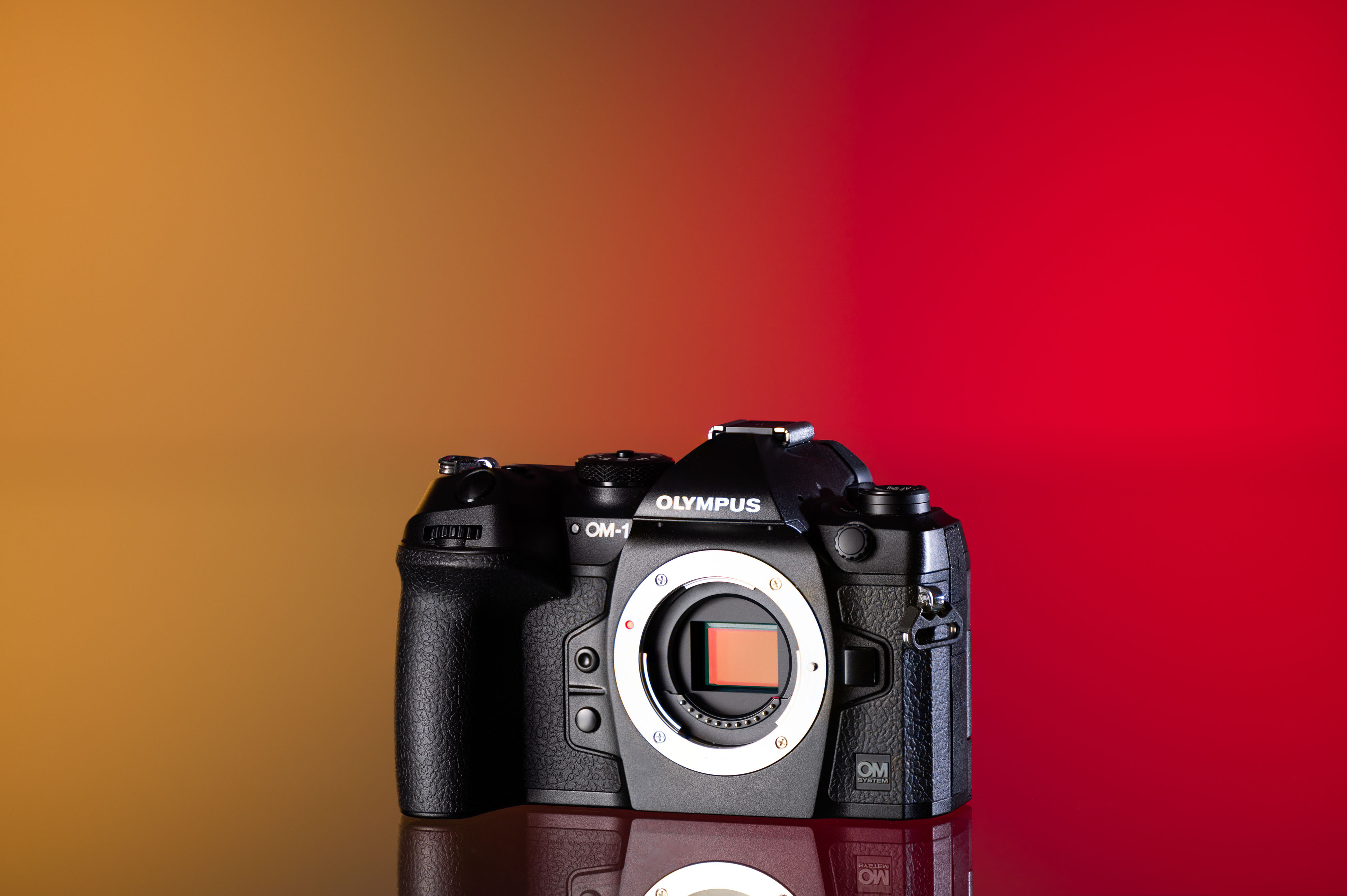 OM System OM-1 de segunda mano sobre un fondo amarillo y rojo