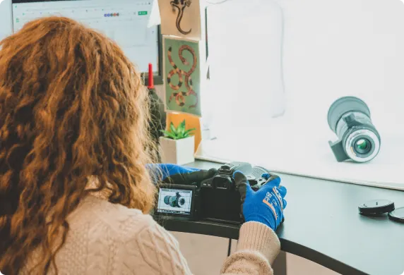 Een productspecialist van MPB maakt met live view op zijn spiegelreflex een productfoto van een gebruikte zoomlens, die in een lichtbak wordt geplaatst.