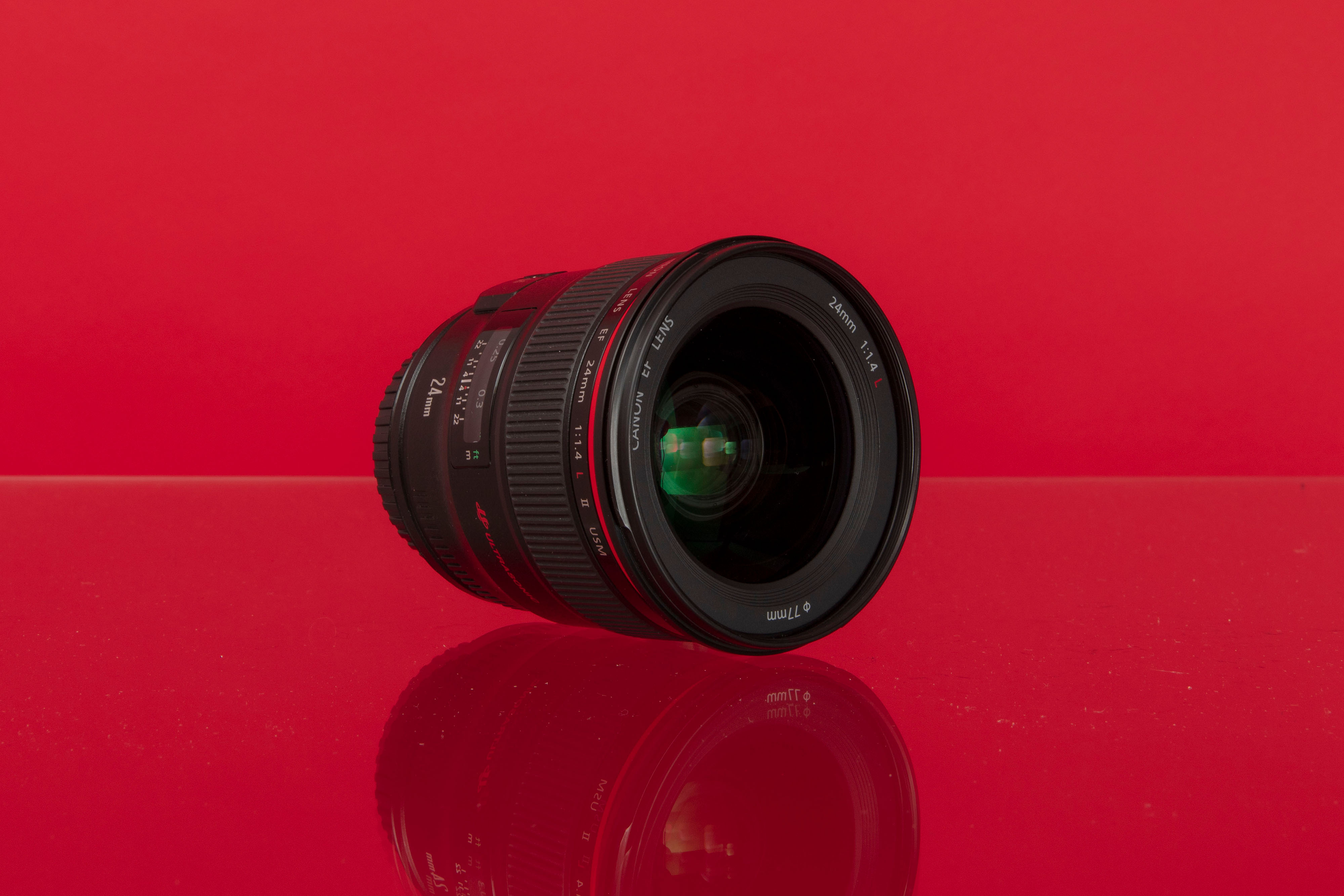 A Canon EF 24mm f/1.4 L II USM wide-angle prime lens against a red background
