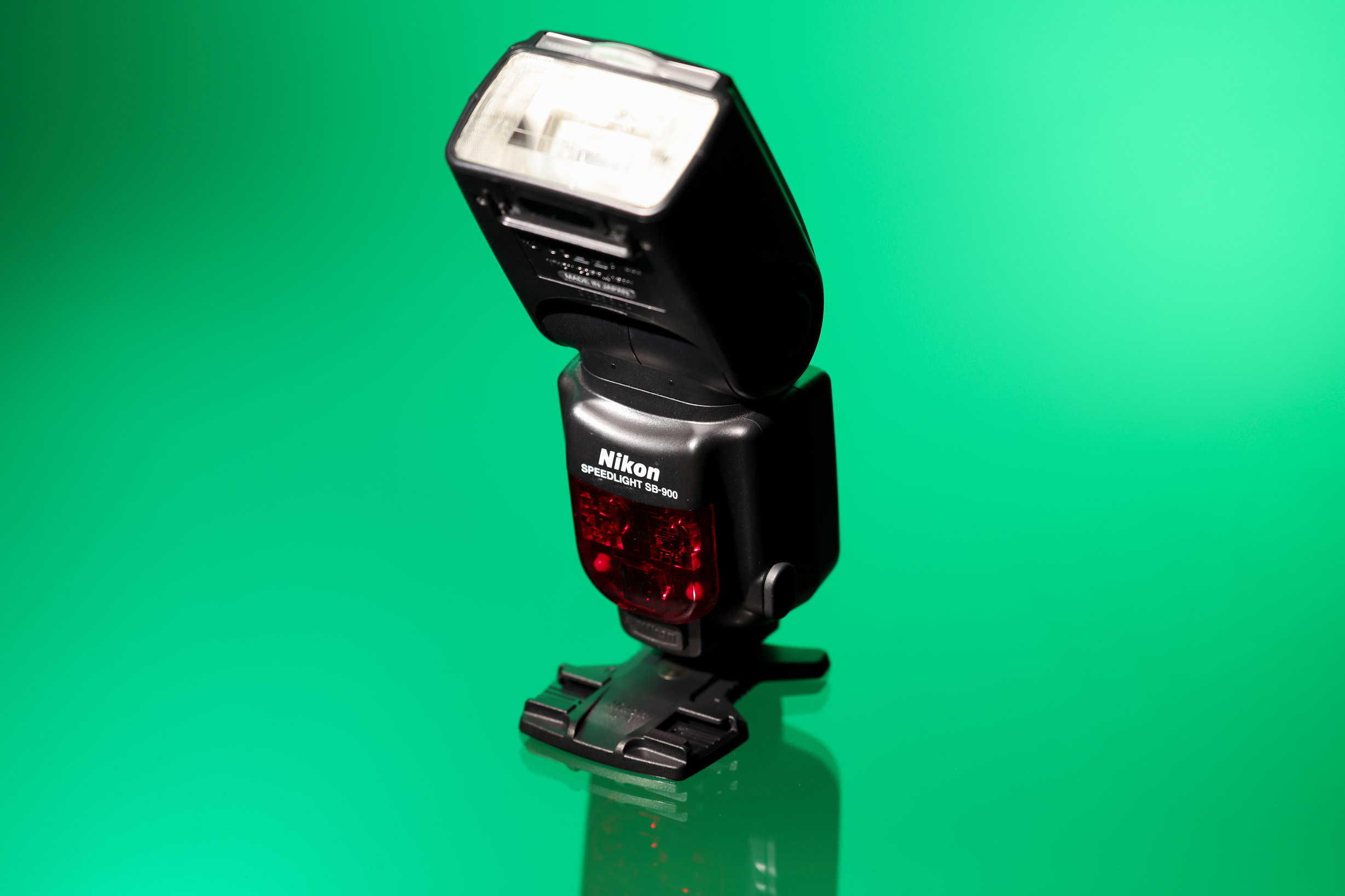 Nikon SB-900 Speedlight against a green background.
