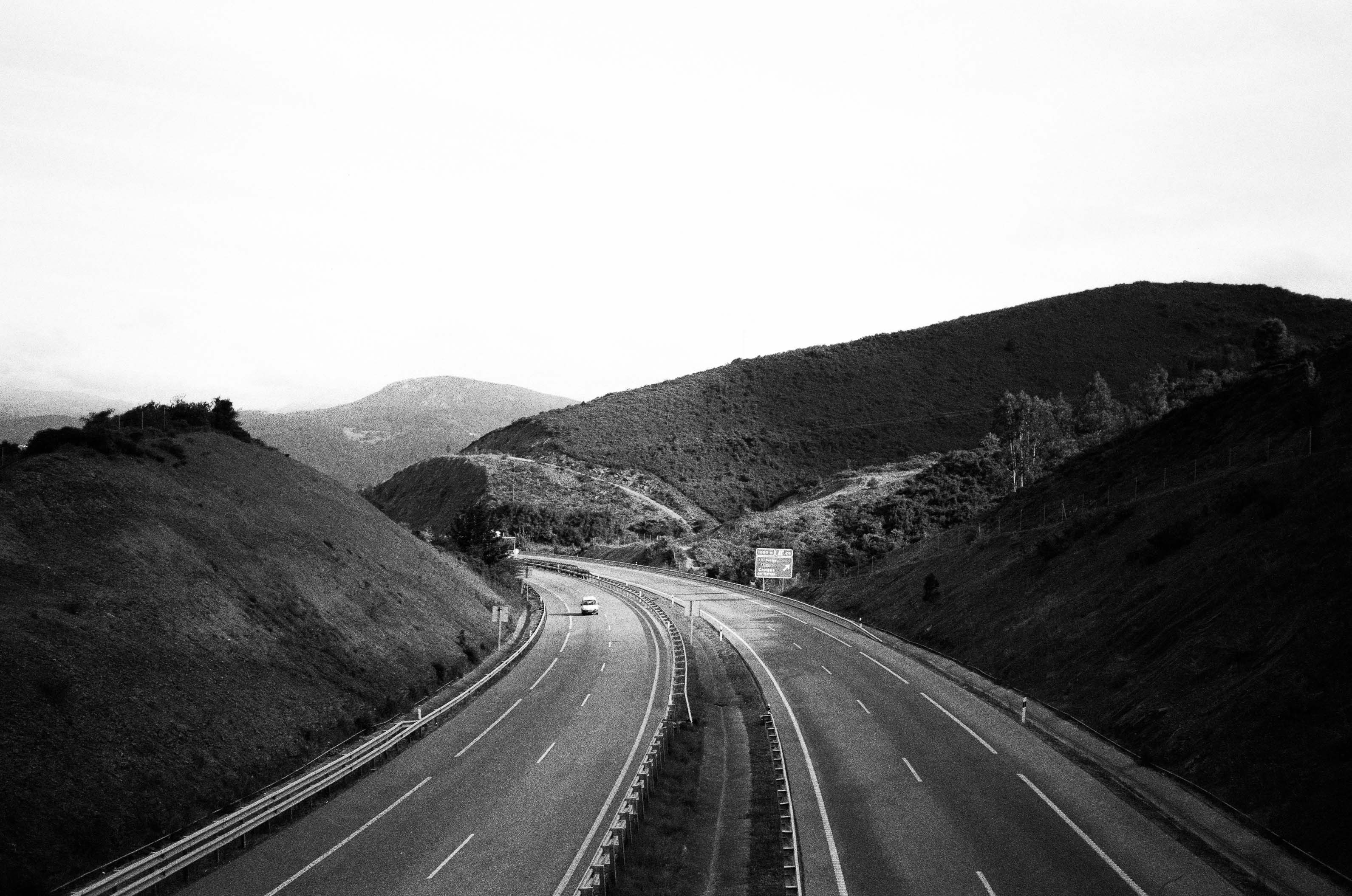 A lonesome car drives on a 4-lane highway in the hills of Asturias, Spain. By Connor Redmond.