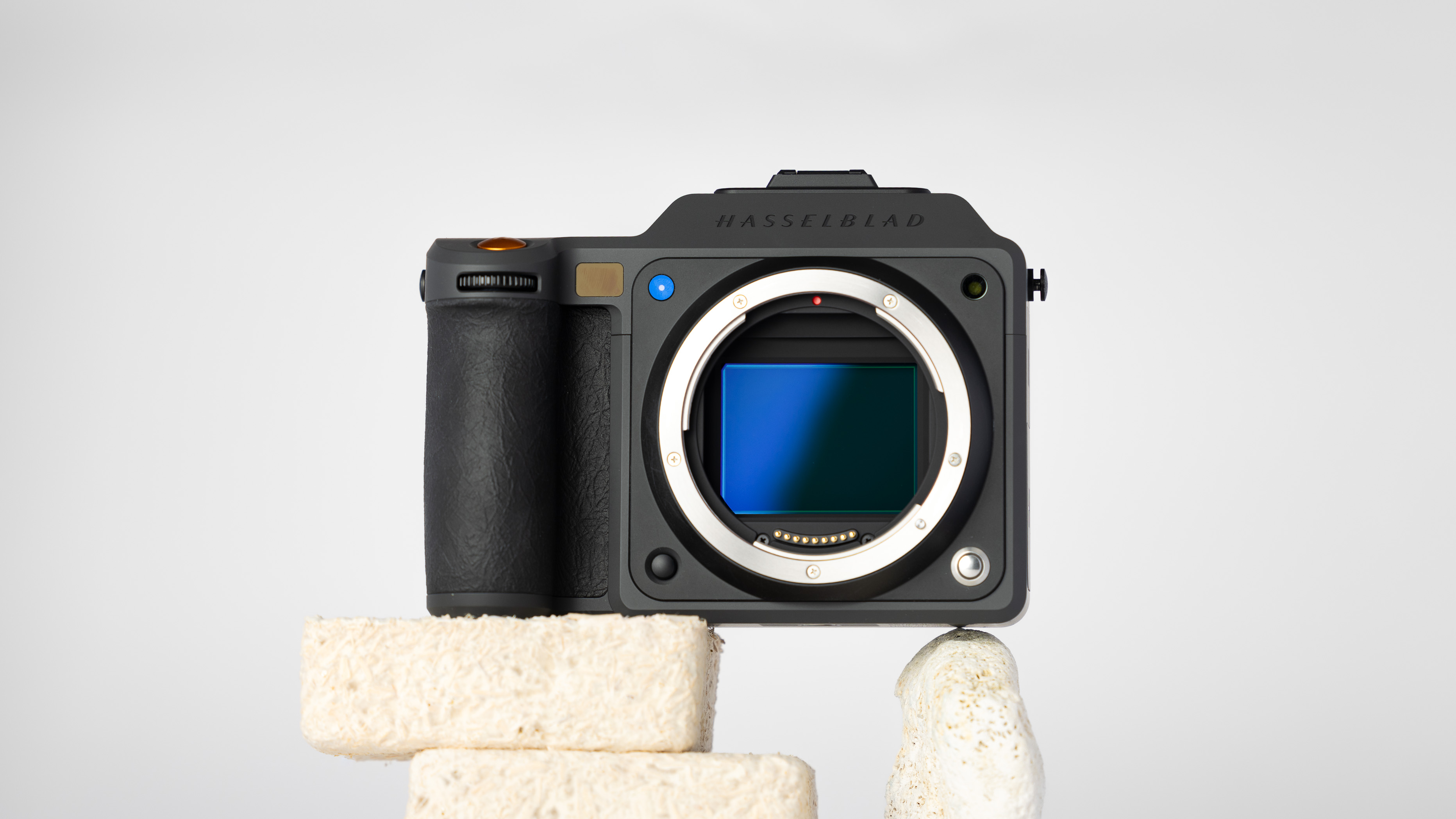 A product shot of a secondhand Hasselblad X2D II 100c camera propped up on a rocky podium