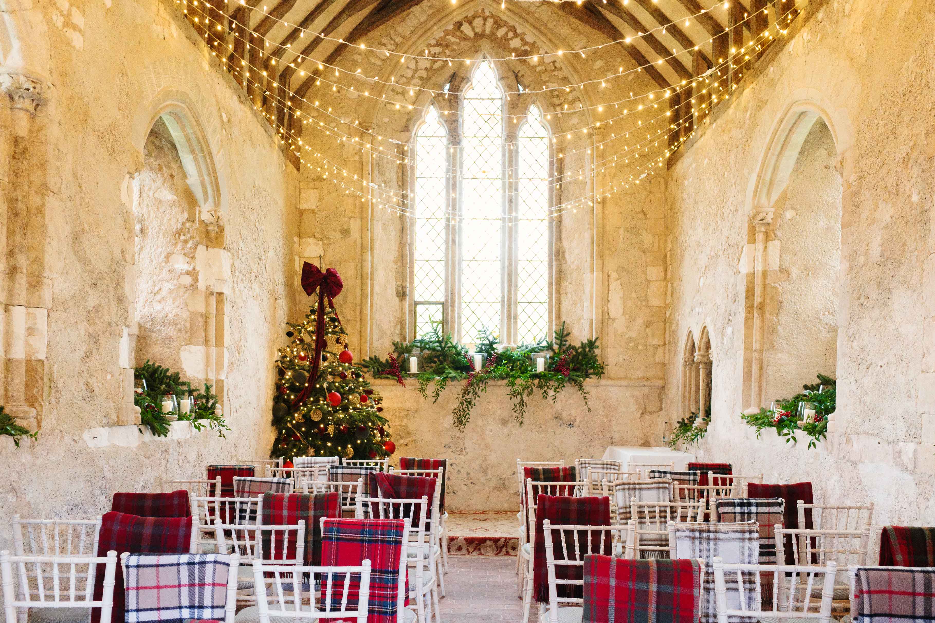 Der warm beleuchtete Innenraum einer weihnachtlich dekorierten Kapelle mit einem Baum, Lichterketten und Reihen von Stühlen mit festlichen Decken. Aufgenommen mit einer Ricoh GR IV.