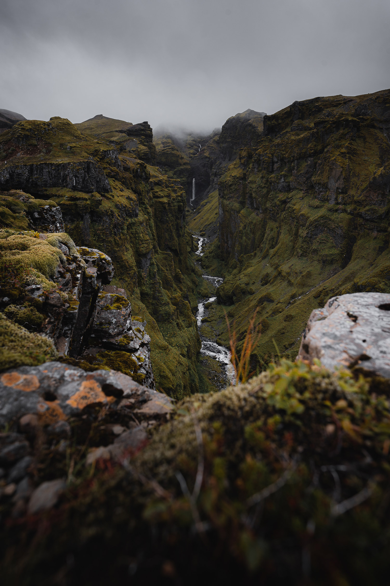 A river running through a valley in Iceland, the hillsides are covered in moss and grass, shot by Paul Watson with a Nikon Z6