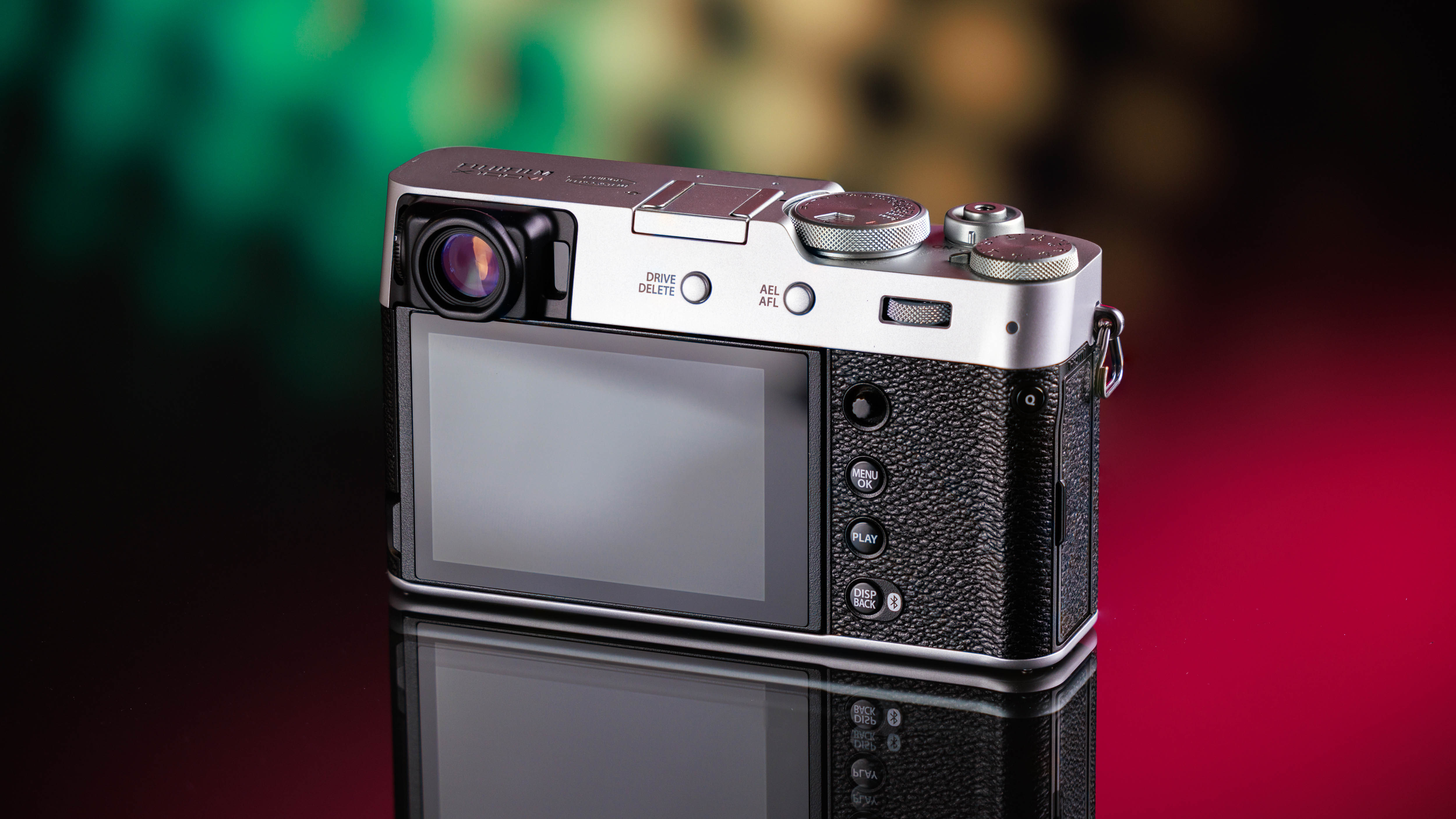 Achterkant van de Fujifilm X100VI op een rode, groene en gele achtergrond