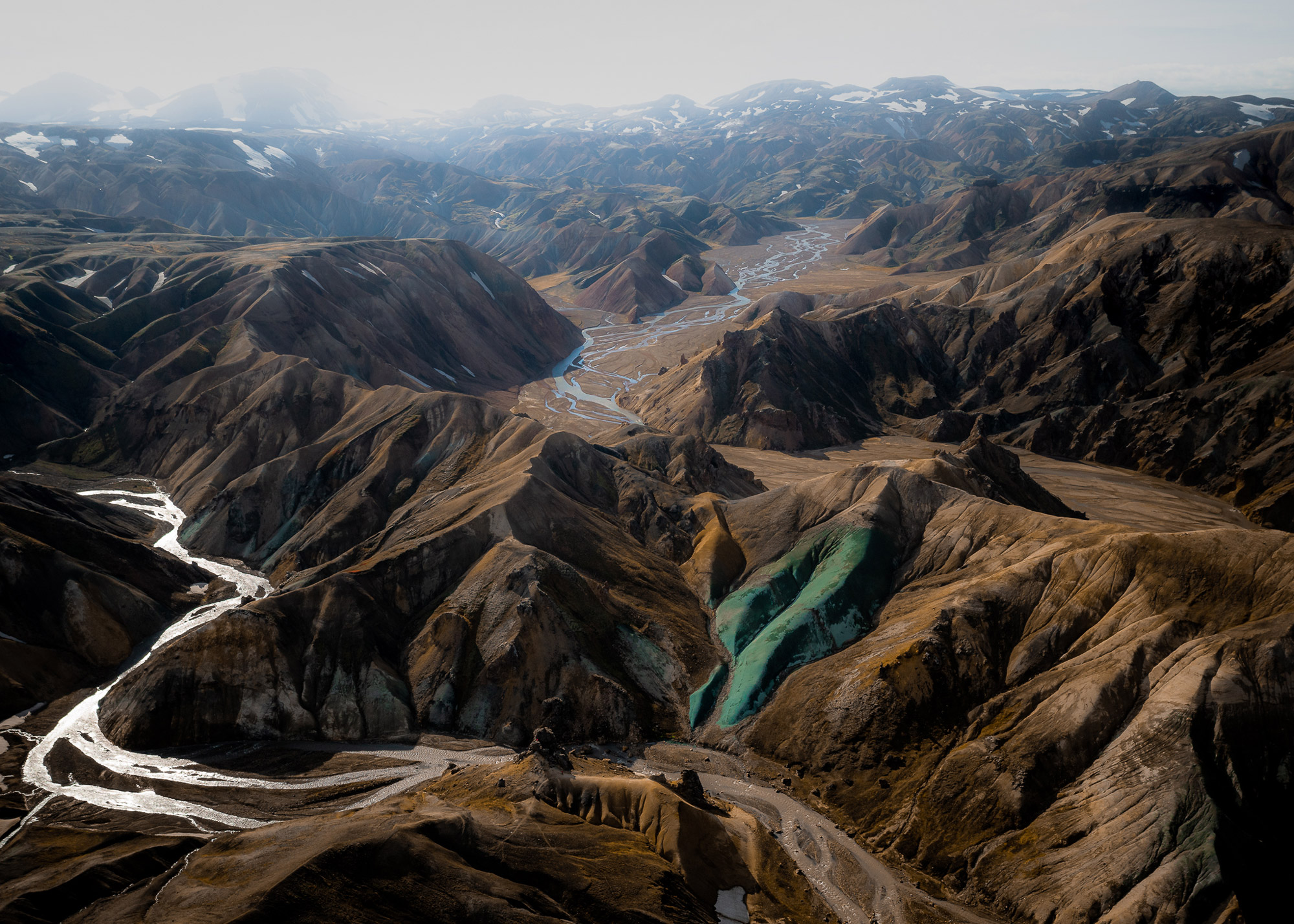 An aerial drone photo of a mountain range and river in Iceland, one mountain has a light-blue side, and a frozen river and track appears on the left, shot by Paul Watson with a DJI Mavic 2 Pro
