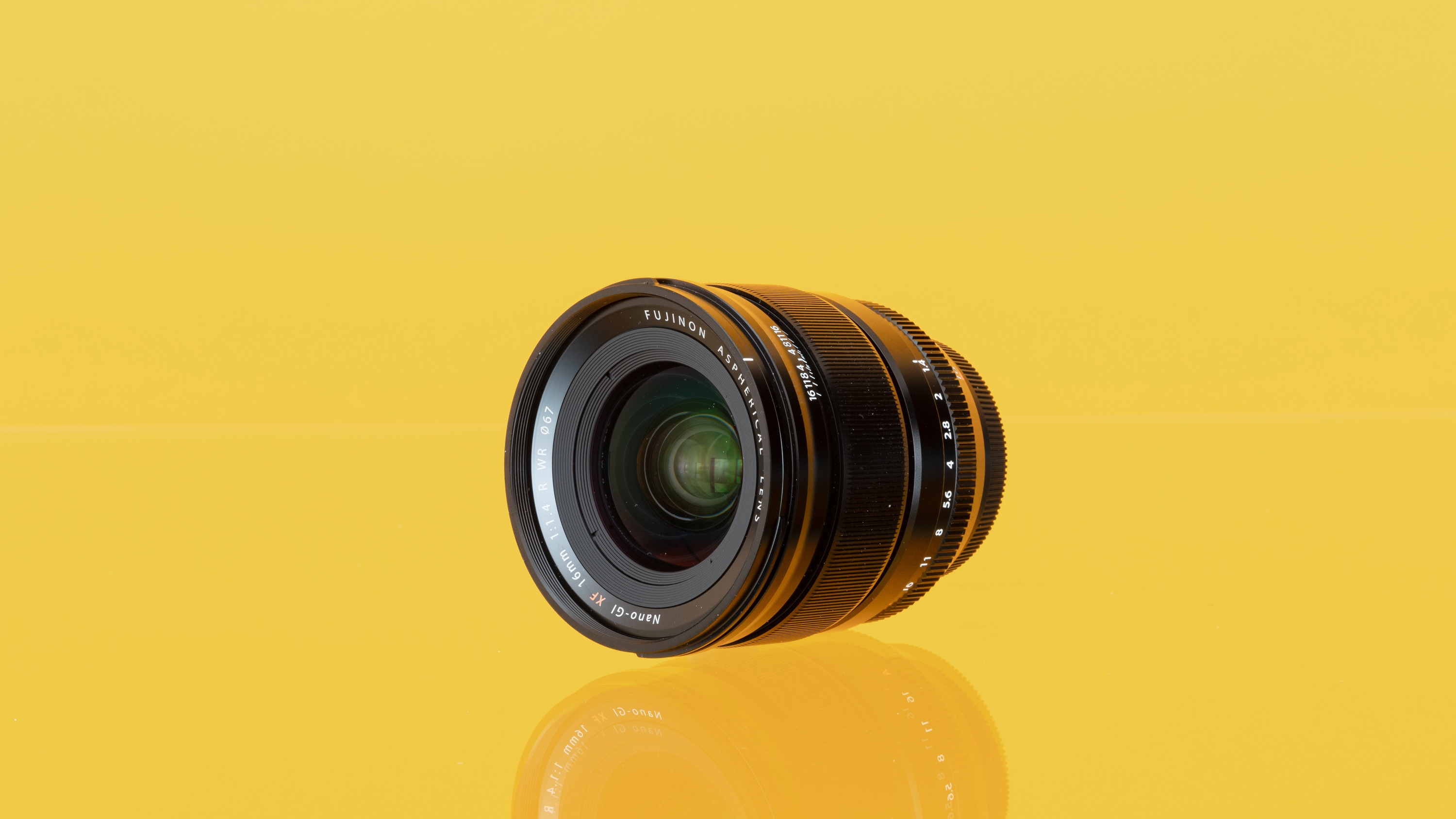 A used Fujifilm XF 16mm f/1.4 R WR from MPB on a yellow background