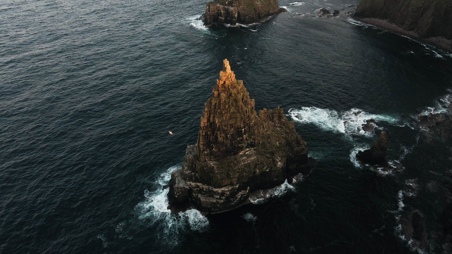 Een dronebeeld van een enorme schoorsteen die uit de zee oprijst in Schotland, een still uit de korte film Truluck van Matt Cannon en Jake Smallwood
