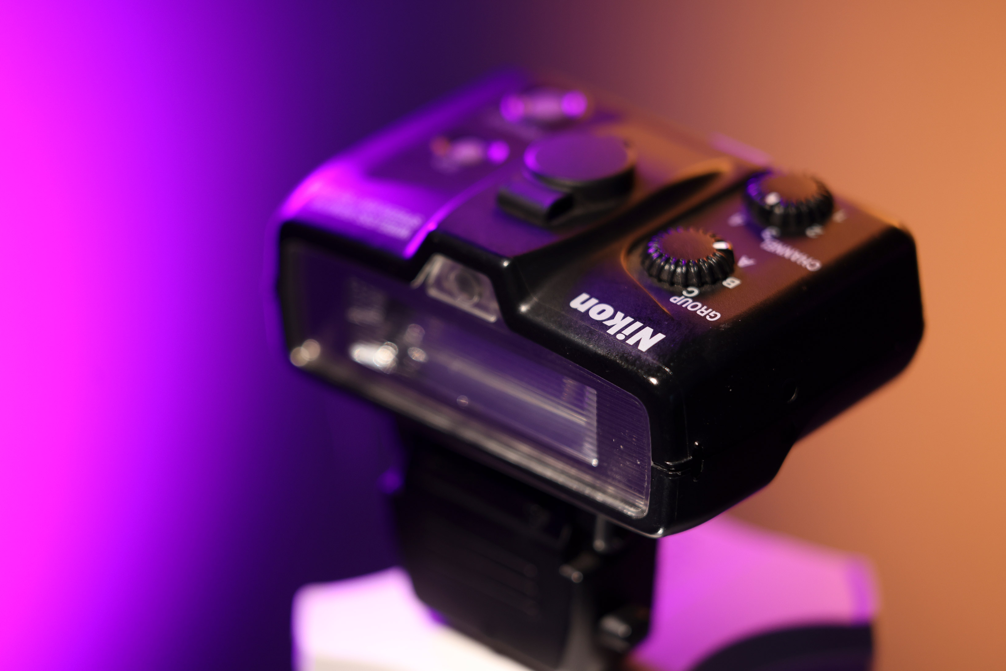 Nikon SB-R200 Speedlight against a purple and peach background.