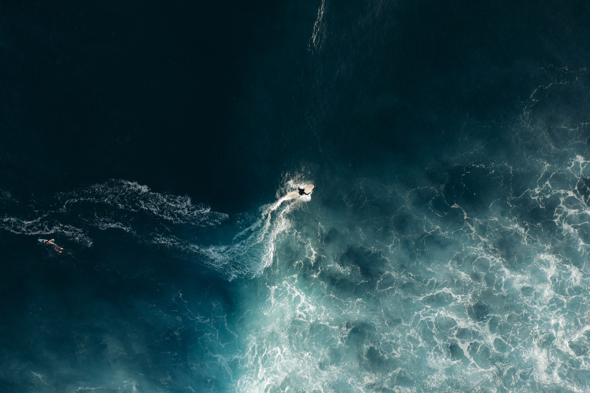 A bird’s eye view of a person surfing on a dark sea, created with a DJI Mavic 2 Pro by travel photographer Harry Pope