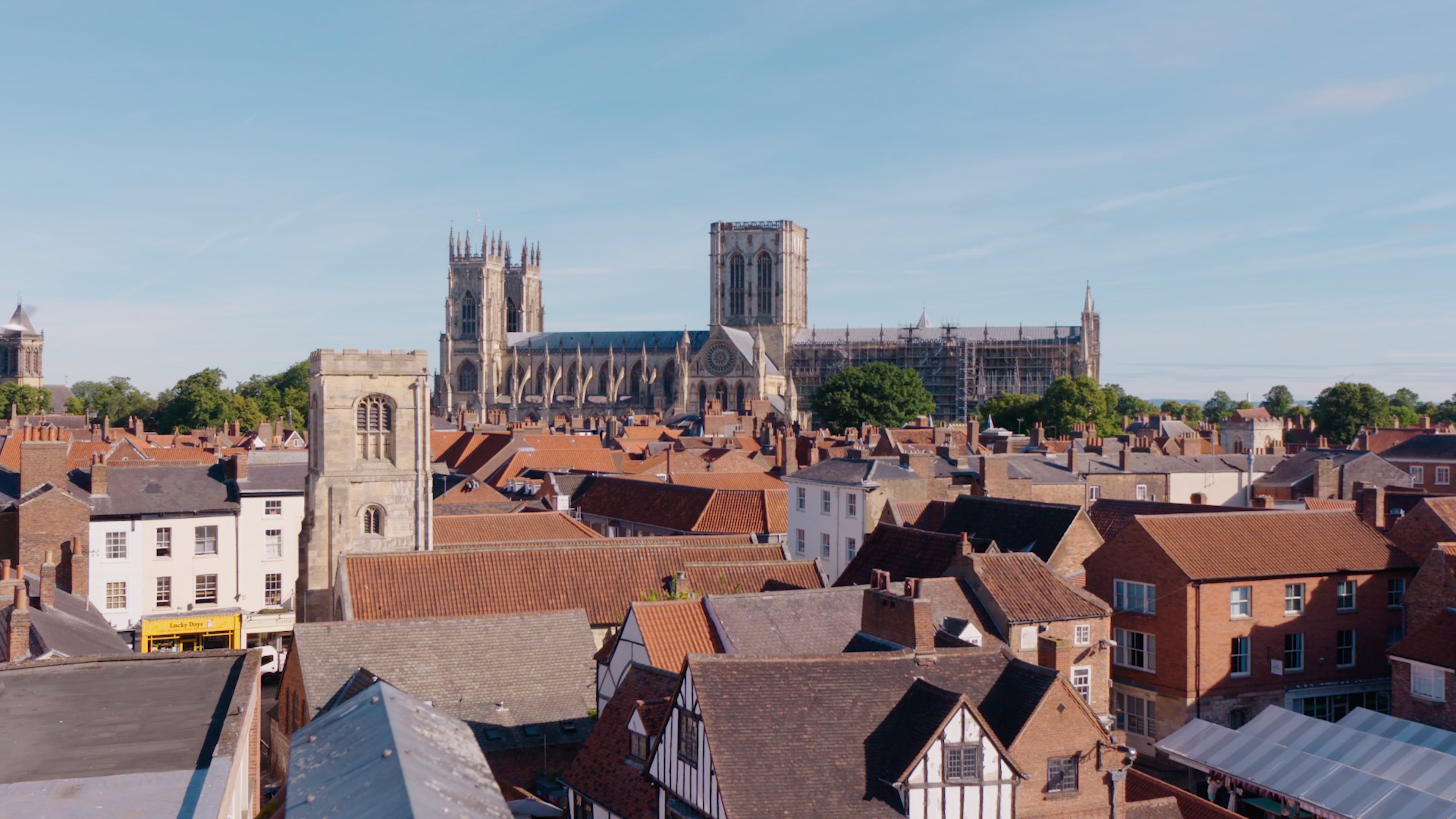 Plan grand angle d'un paysage urbain traditionnel de York, avec des maisons traditionnelles en brique et en bois au premier plan et la cathédrale de York à l'arrière-plan.