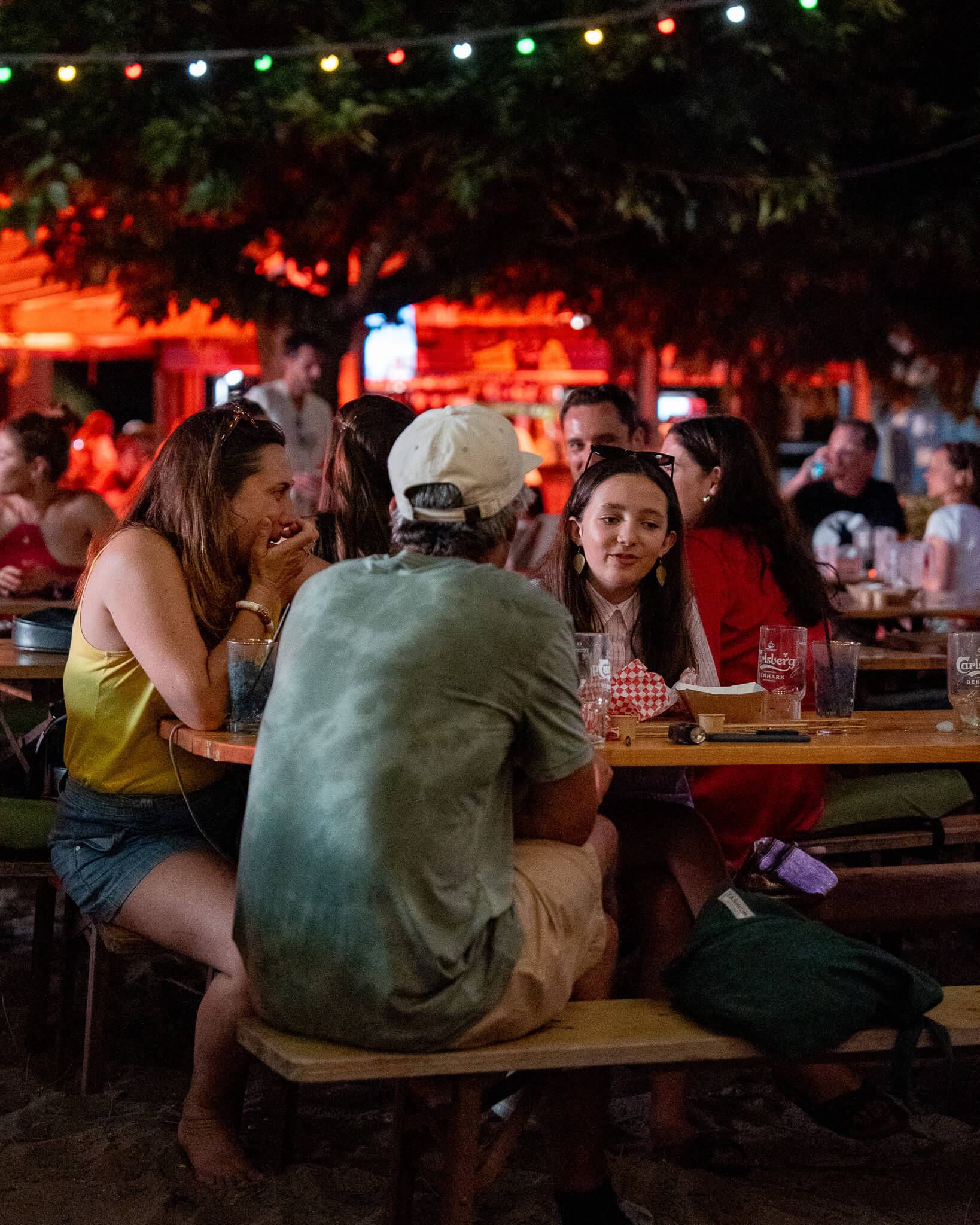 
Trois personnes sont assises autour d’une table en soirée et discutent en buvant un verre. Photo prise avec le Sony A9 III par Paul Lavoine

