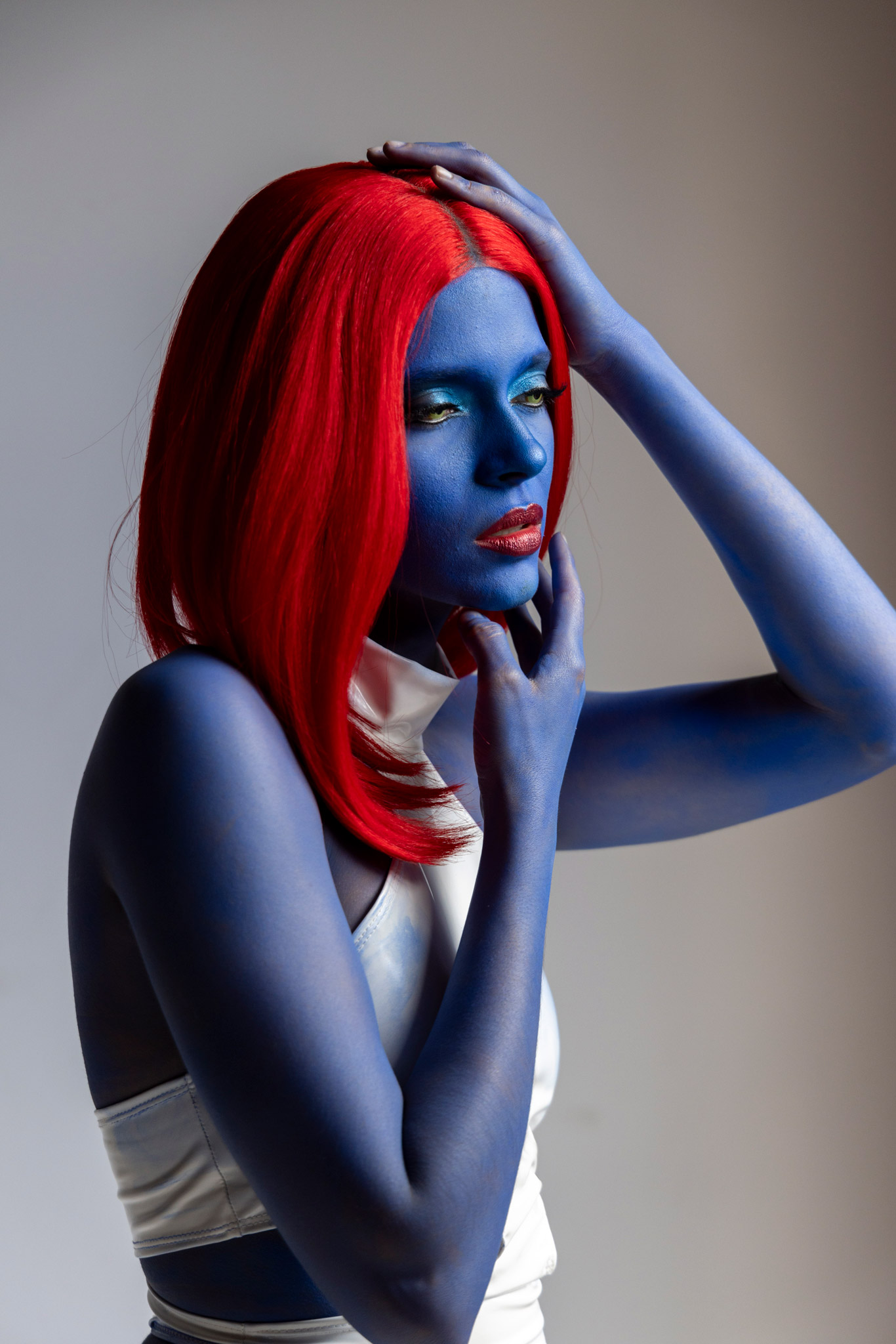 Mystique cosplayer poses against a gray backdrop.
