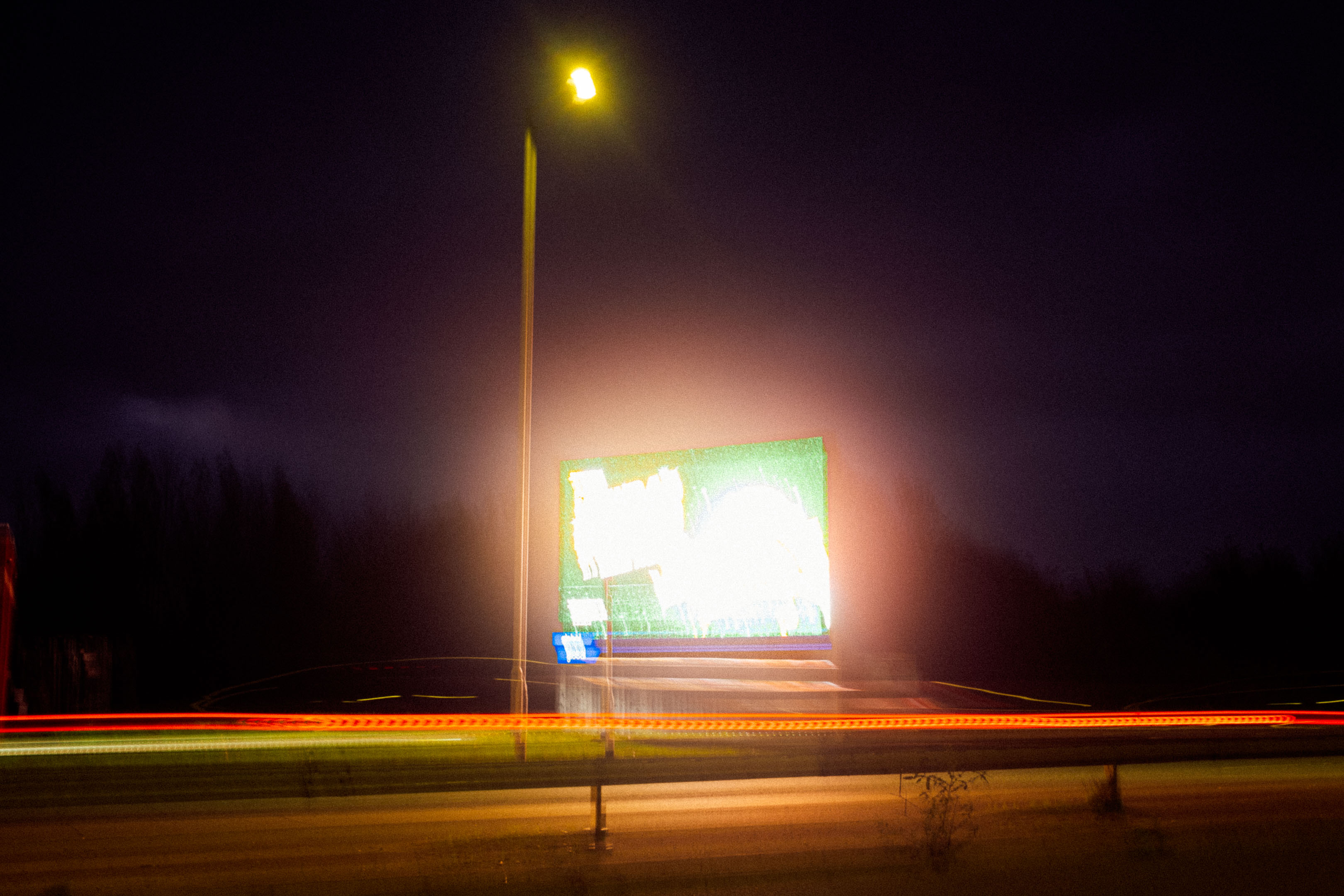 An advertisement sign at night taken on a long exposure creating an abstract image. Fujifilm X100VI by Connor Redmond.