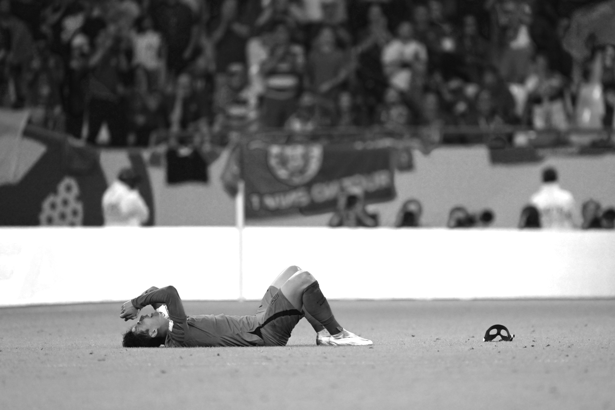 Ein Schwarz-Weiß-Foto von Südkoreas Kapitän Son Heung-min, der nach dem 2:1-Sieg seiner Mannschaft gegen Portugal, der das Weiterkommen in die K.o.-Runde der WM 2022 gesichert hat, seine Schutzmaske ablegt und auf dem Boden zusammenbricht, aufgenommen von Ryu Voelkel mit einer Nikon Z9.